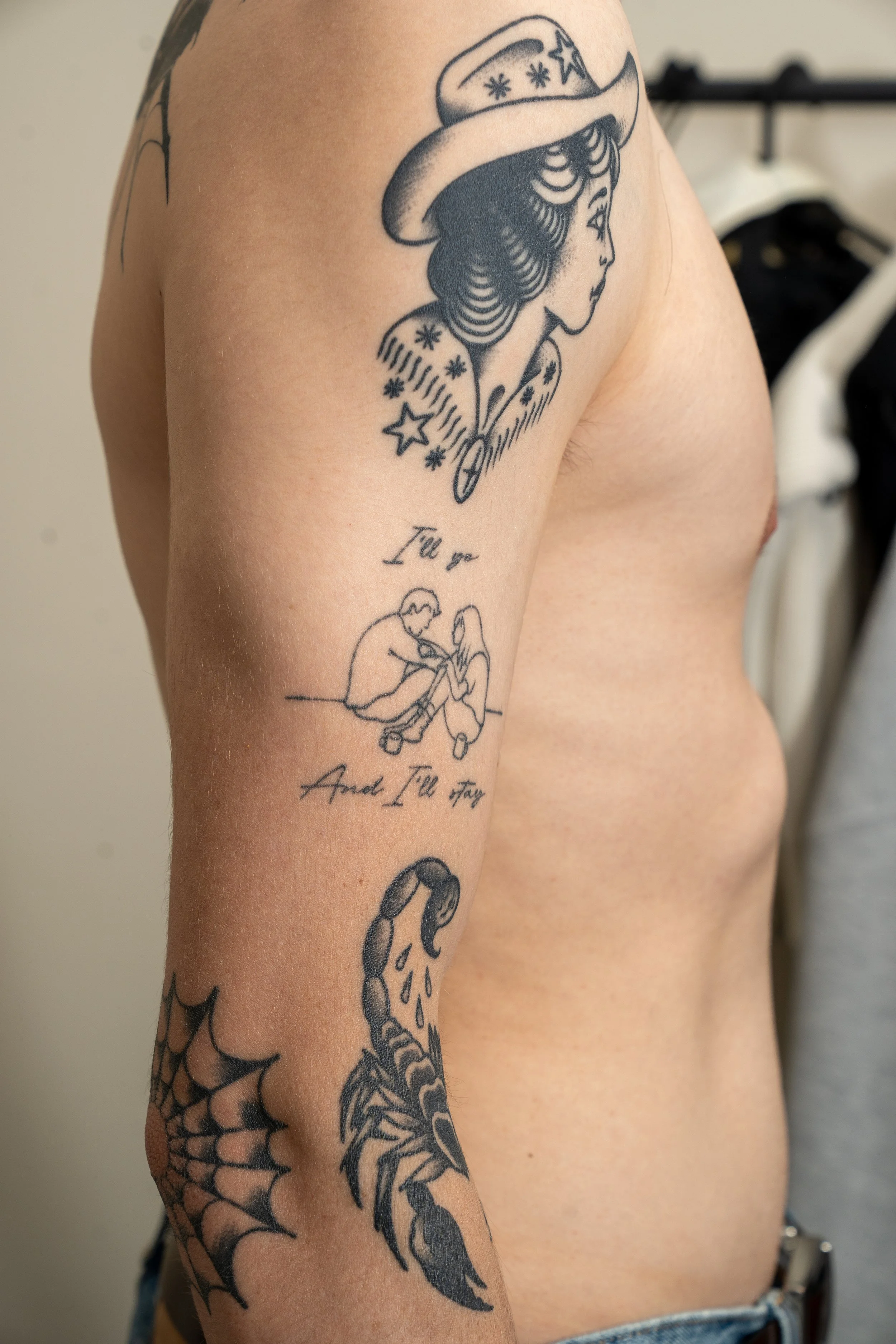 Tattoo of a woman with a hat, a child sitting, and a spider web on the arm.