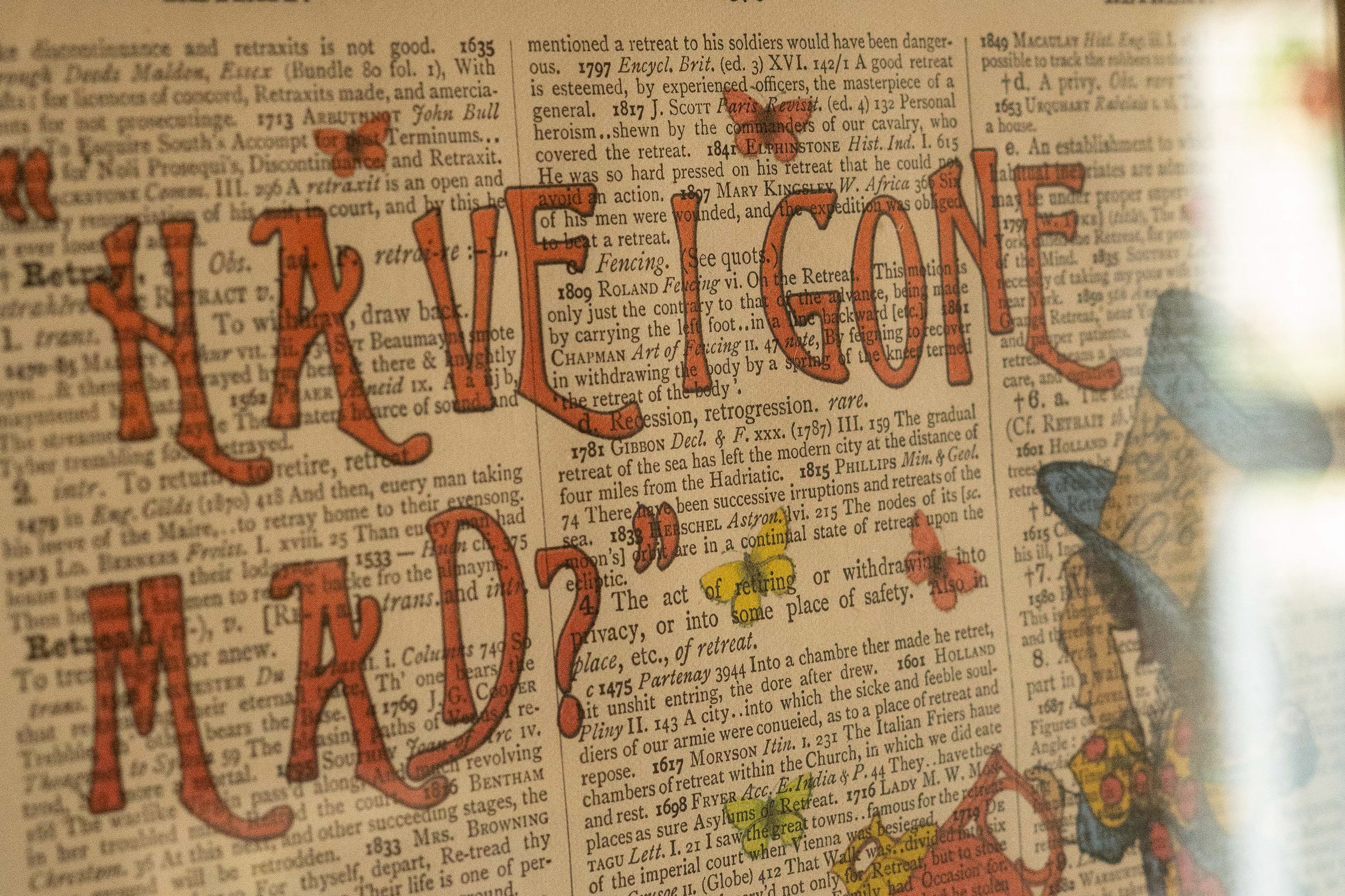 A page from a book or dictionary with the phrase "Take a break" written in large, red letters across the text. The words are hand-drawn and overlay the printed text.