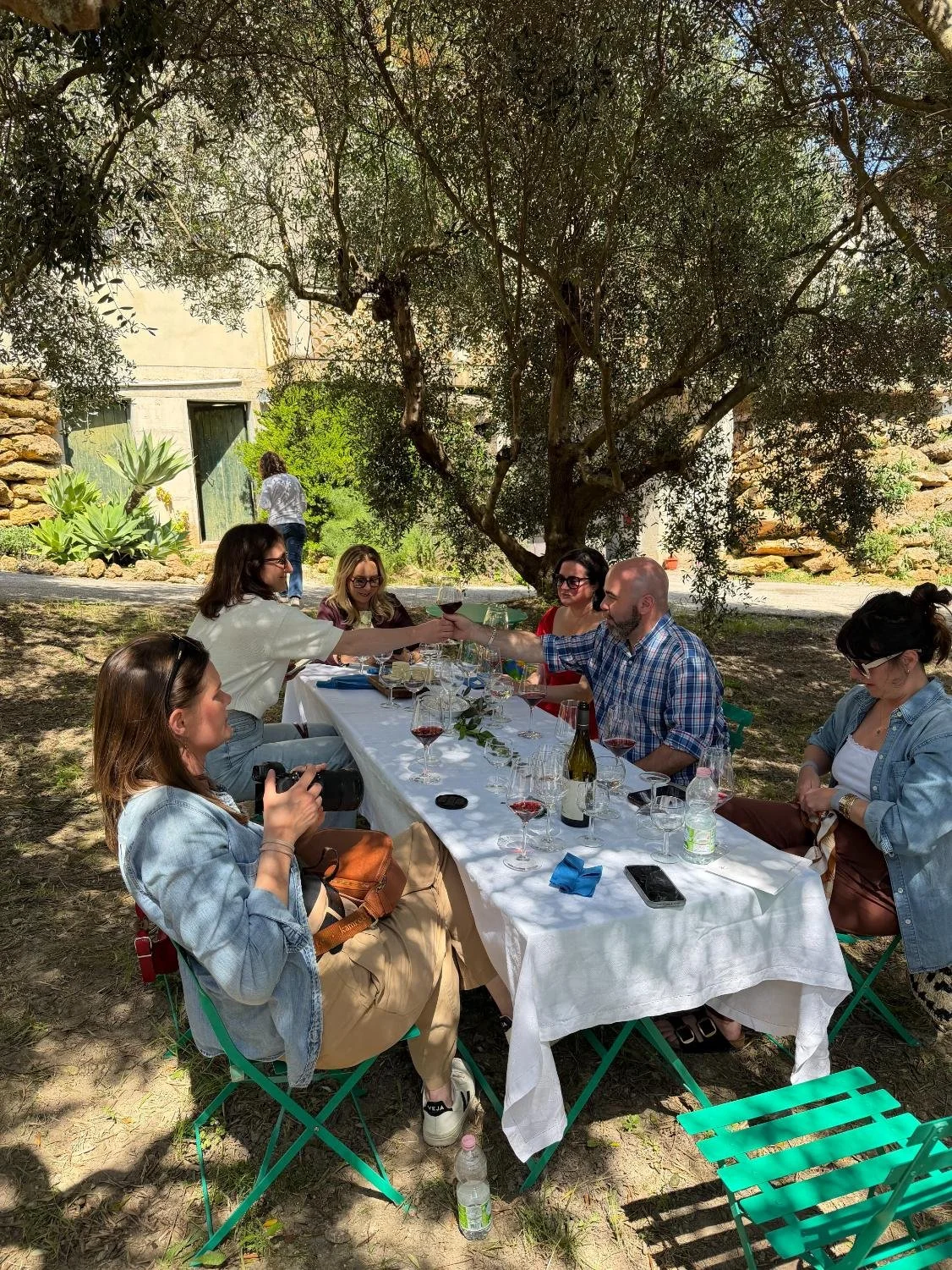 Image of people smiling outside eating dinner at a table with wine glasses
