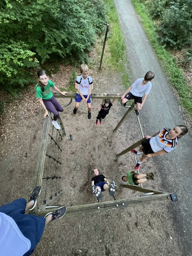 Kinder spielen auf einem Klettergerüst im Freien, Blick von oben nach unten.