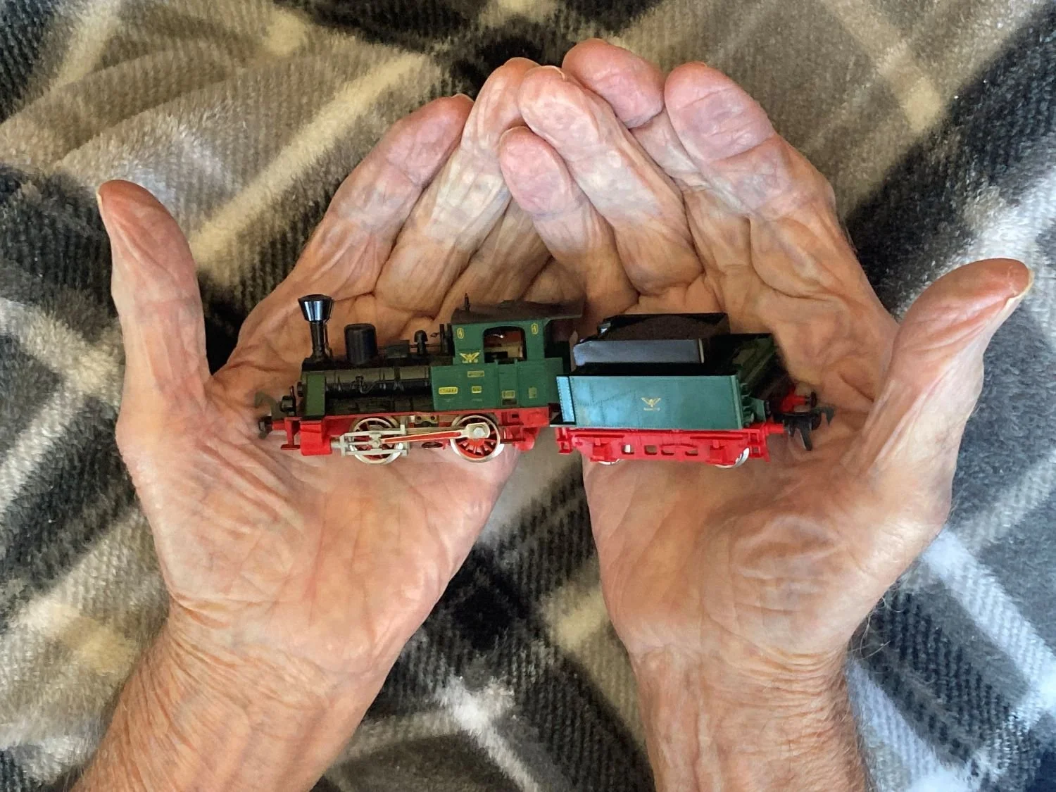 Elderly man's hands holding a toy train
