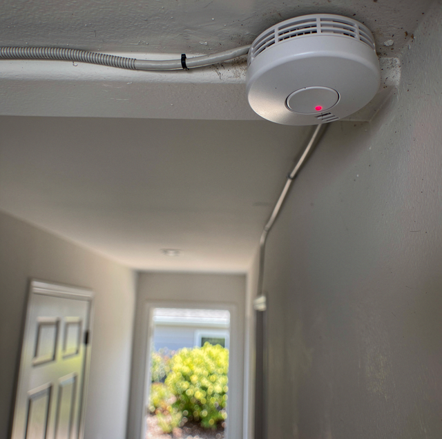 Interconnected smoke alarms sounding on bedroom ceiling