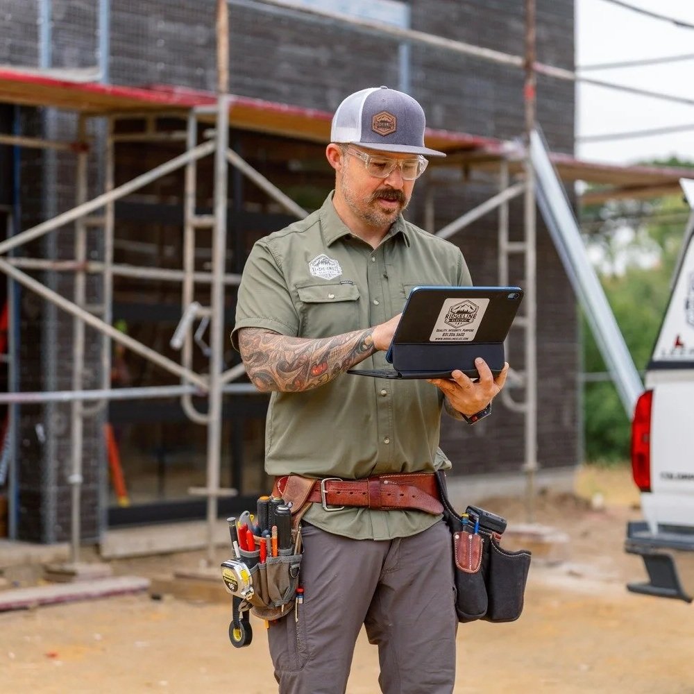 Electrician using a tablet at a construction site while diagnosing electrical systems, illustrating professional troubleshooting of outlets, circuits, GFCI protection, and residential electrical service issues.