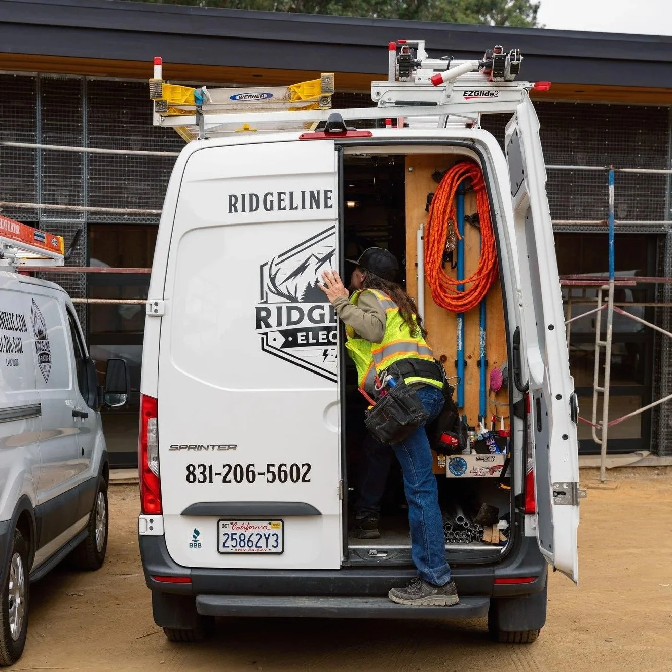 Electrician accessing tools and equipment from a service van while preparing to inspect or remediate residential aluminum wiring, addressing potential connection hazards and electrical safety concerns in older homes.