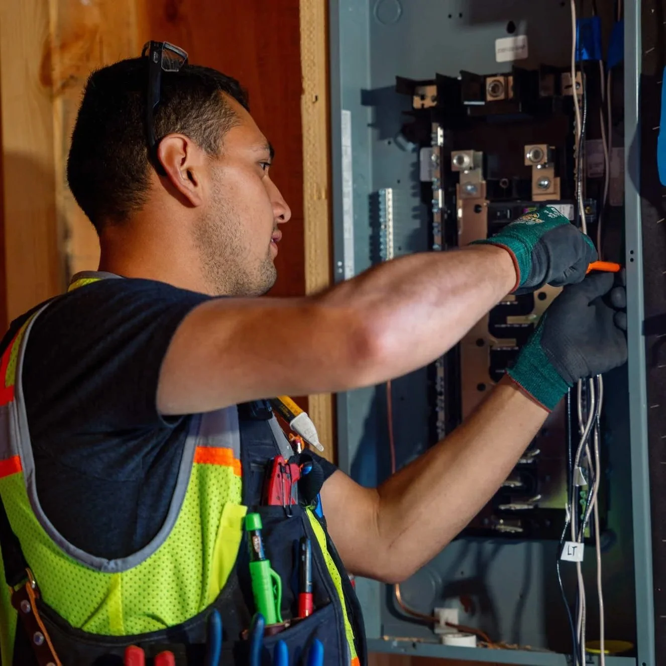 Commercial electrician inspecting an electrical panel, checking breakers and wiring connections during preventive maintenance to improve safety, reliability, and compliance with commercial electrical inspection requirements.