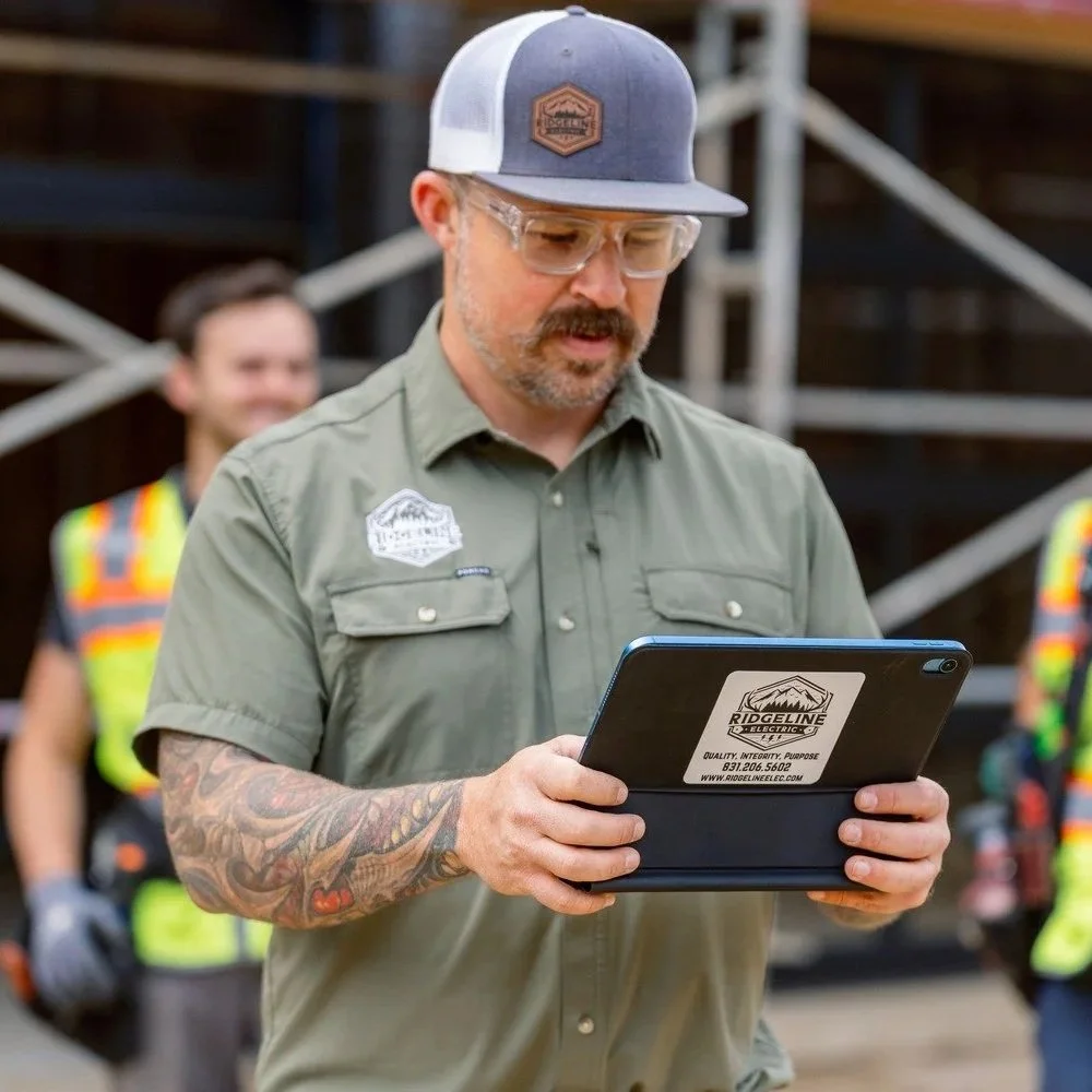 Electrical contractor reviewing installation details on a tablet at a construction site, illustrating project planning, permitting, and electrical coordination required for a safe hot tub installation.