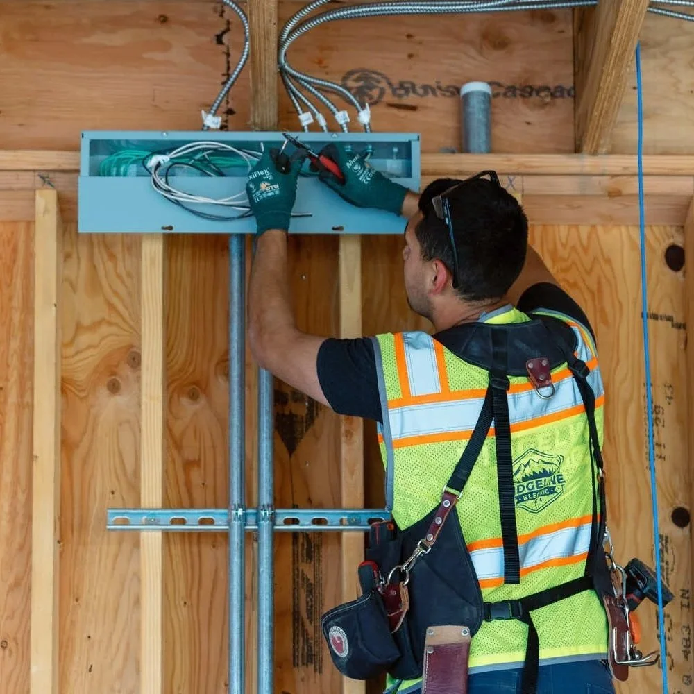 Electrician installing electrical equipment inside a multi-unit building under construction, illustrating maintenance and troubleshooting of shared electrical systems that can cause lights to flicker across multiple units.