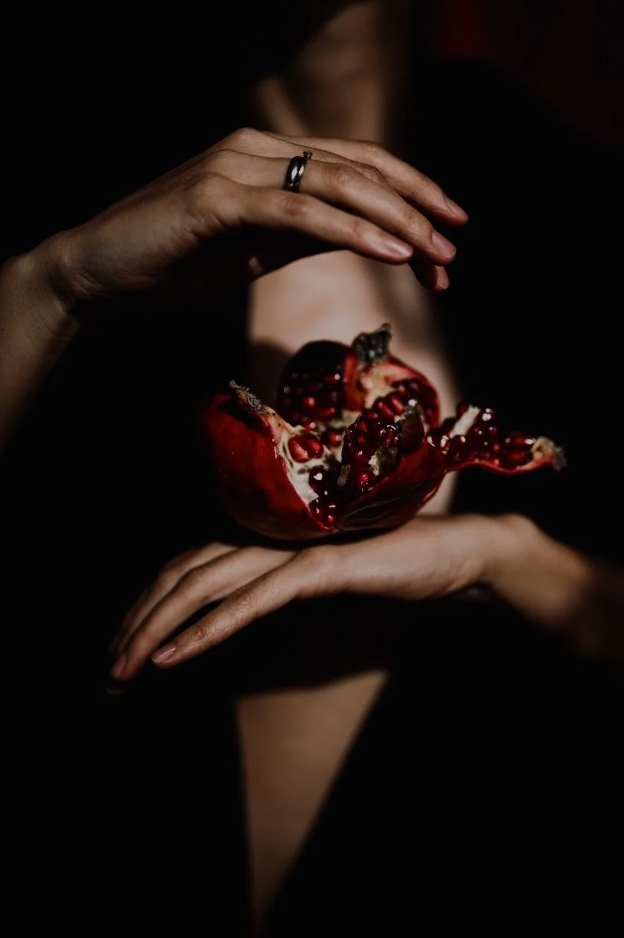 Sunlight filters into a narrow, winding slot canyon with smooth, layered sandstone walls in shades of orange, brown, and black.