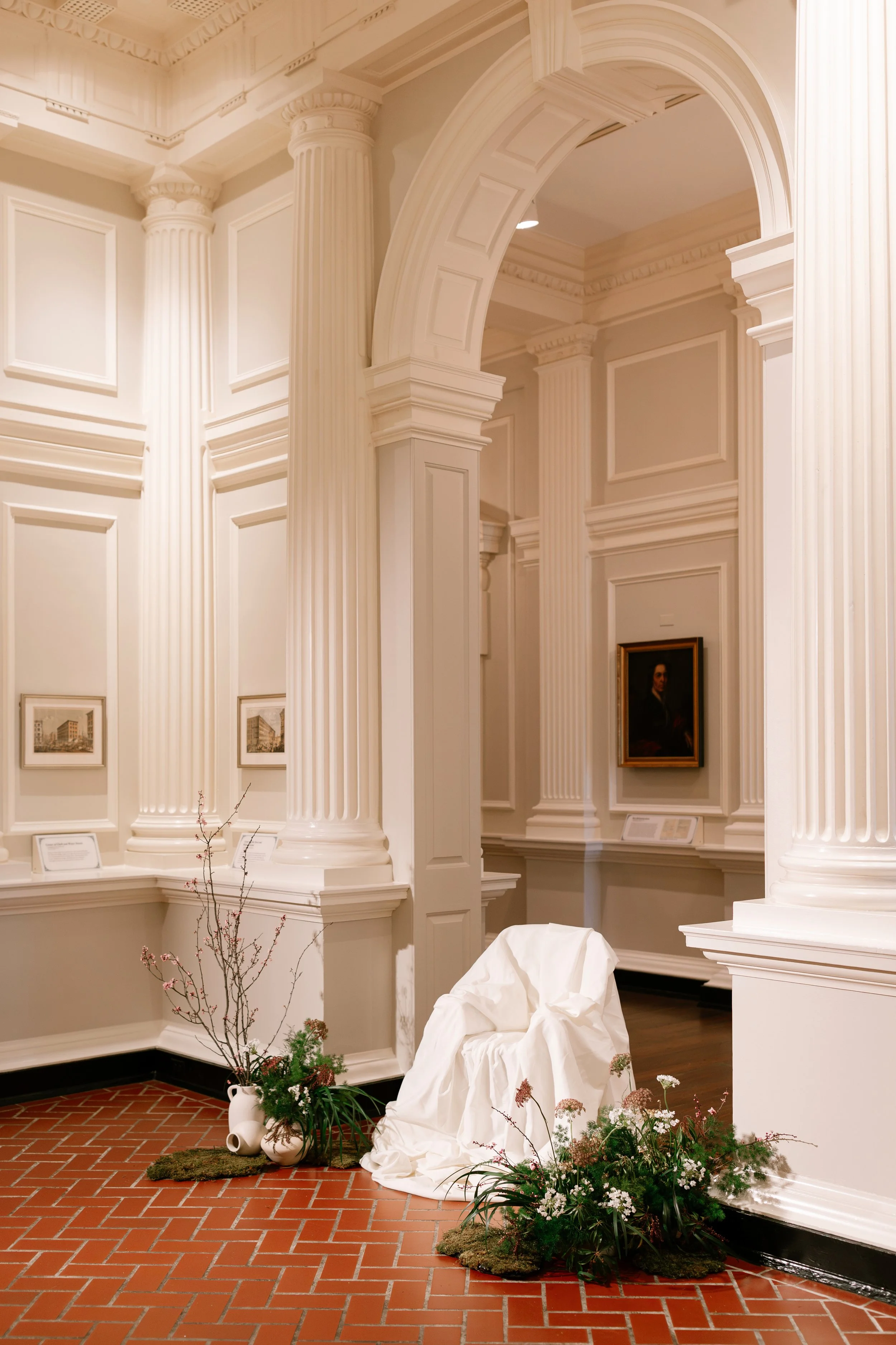 Sculptural ceremony florals in an art gallery setting with organic branches and white blooms
