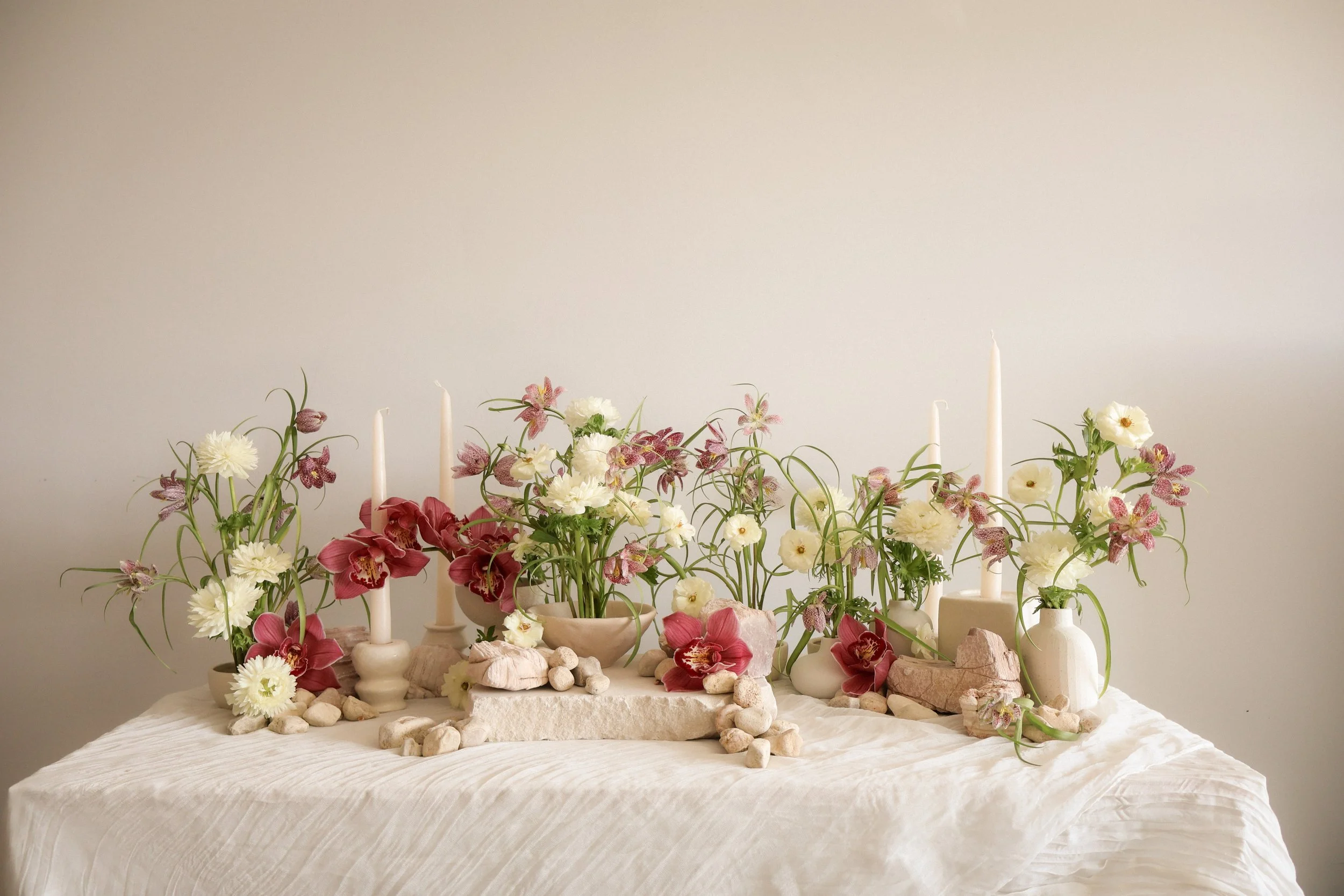Modern textural floral arrangement with white, blush, and soft purple blooms, styled with candles and natural stone accents