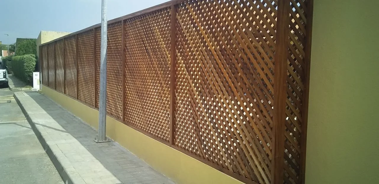Bela cerca de madeira ao longo de uma calçada, com poste e sombra na parte superior.
