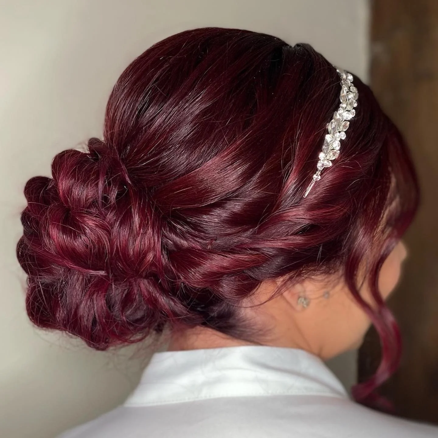 Close-up of a woman's hairstyle featuring a red and purple braided updo with a sparkly crystal hair accessory.