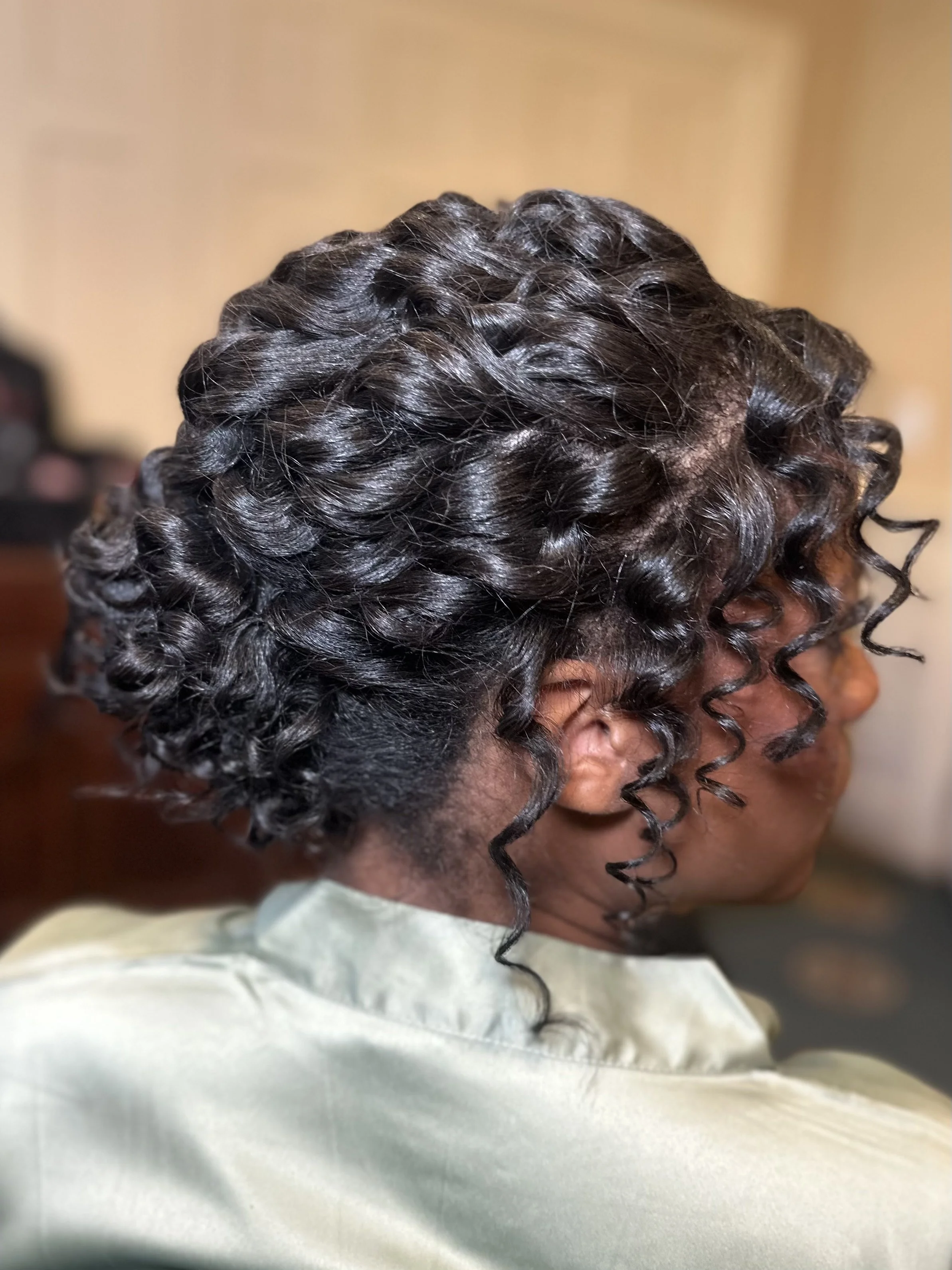 Close-up of a person's head showing dark curly hair styled in tight twists.