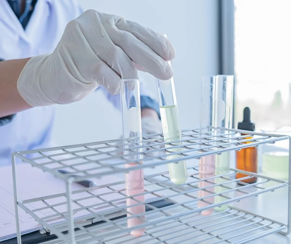 gloved hand holding test tubes