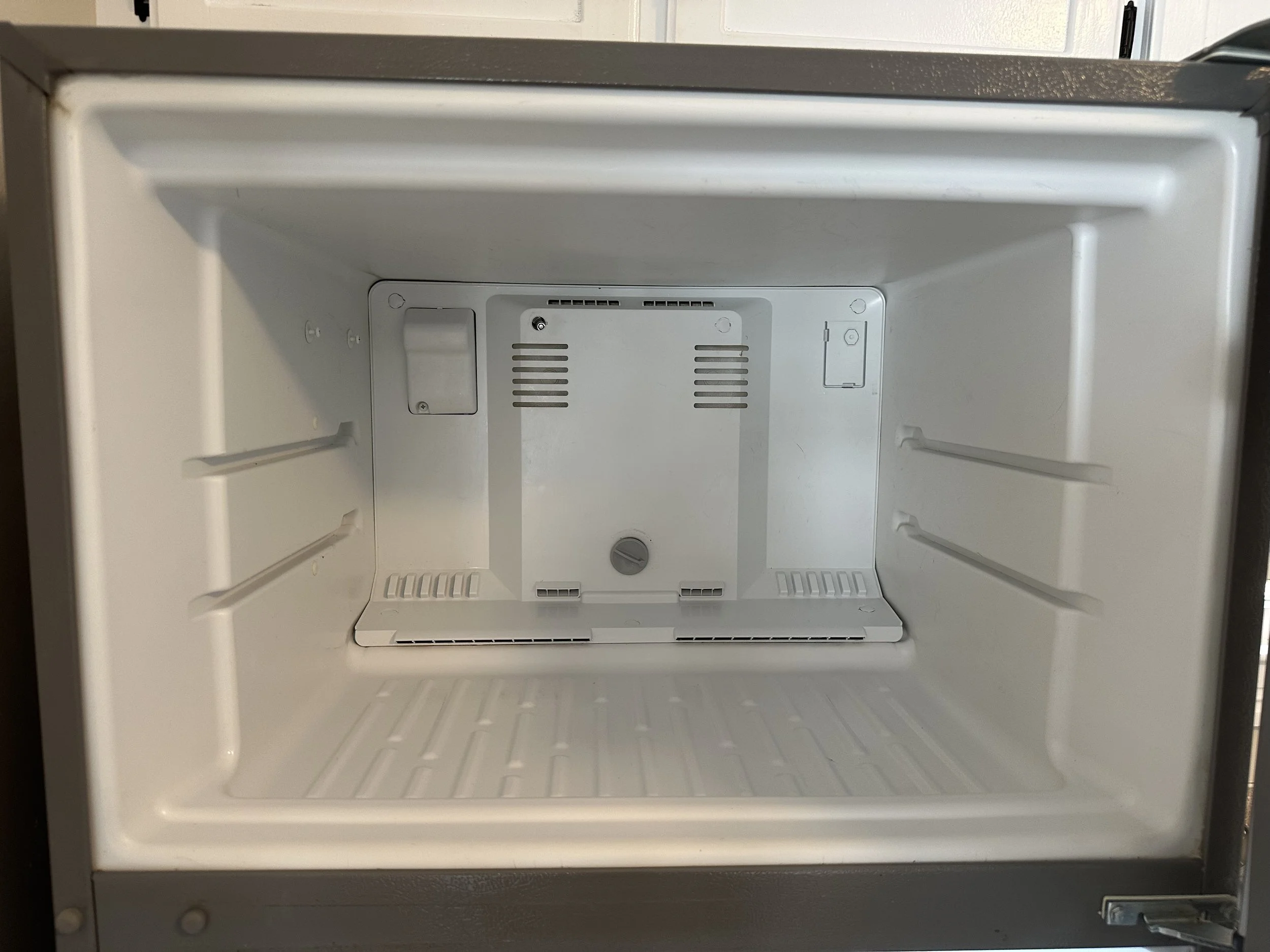 Empty white refrigerator interior with shelves and compartments.