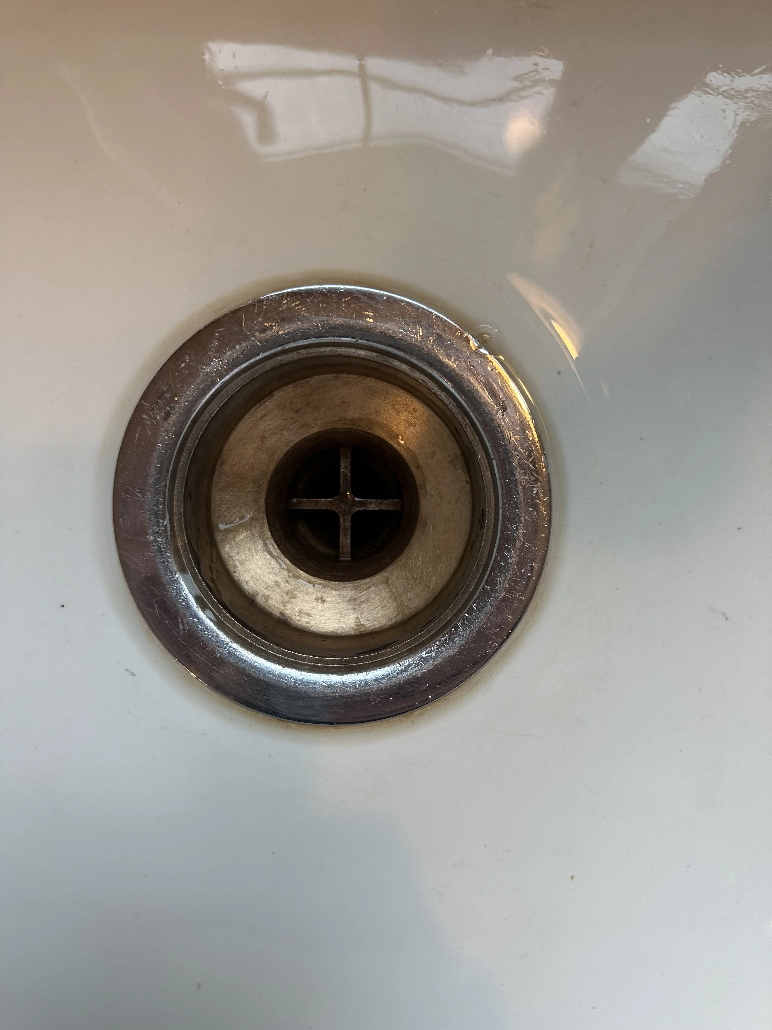 Kitchen sink drain with a cross-shaped stopper inside.