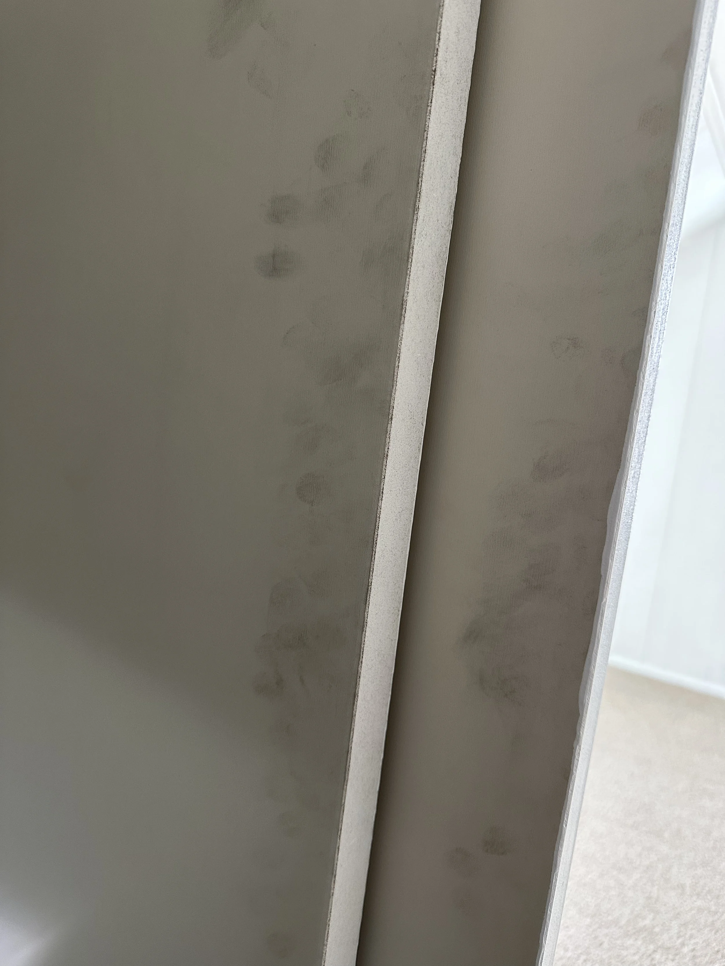 Close-up of drywall with visible joint compound and tape applied during drywall finishing.