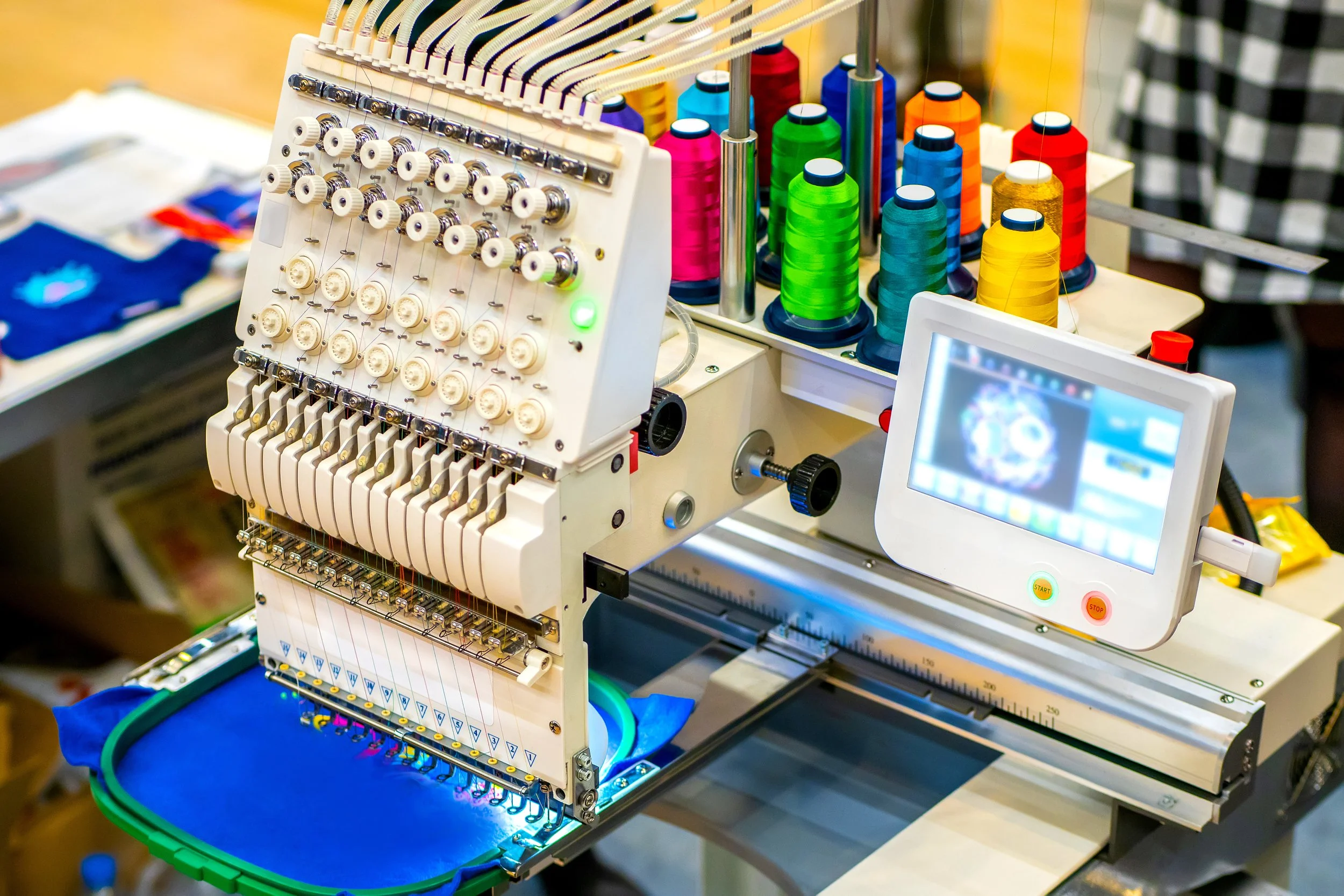 A computerized embroidery machine with colorful spools of thread and a digital control panel.