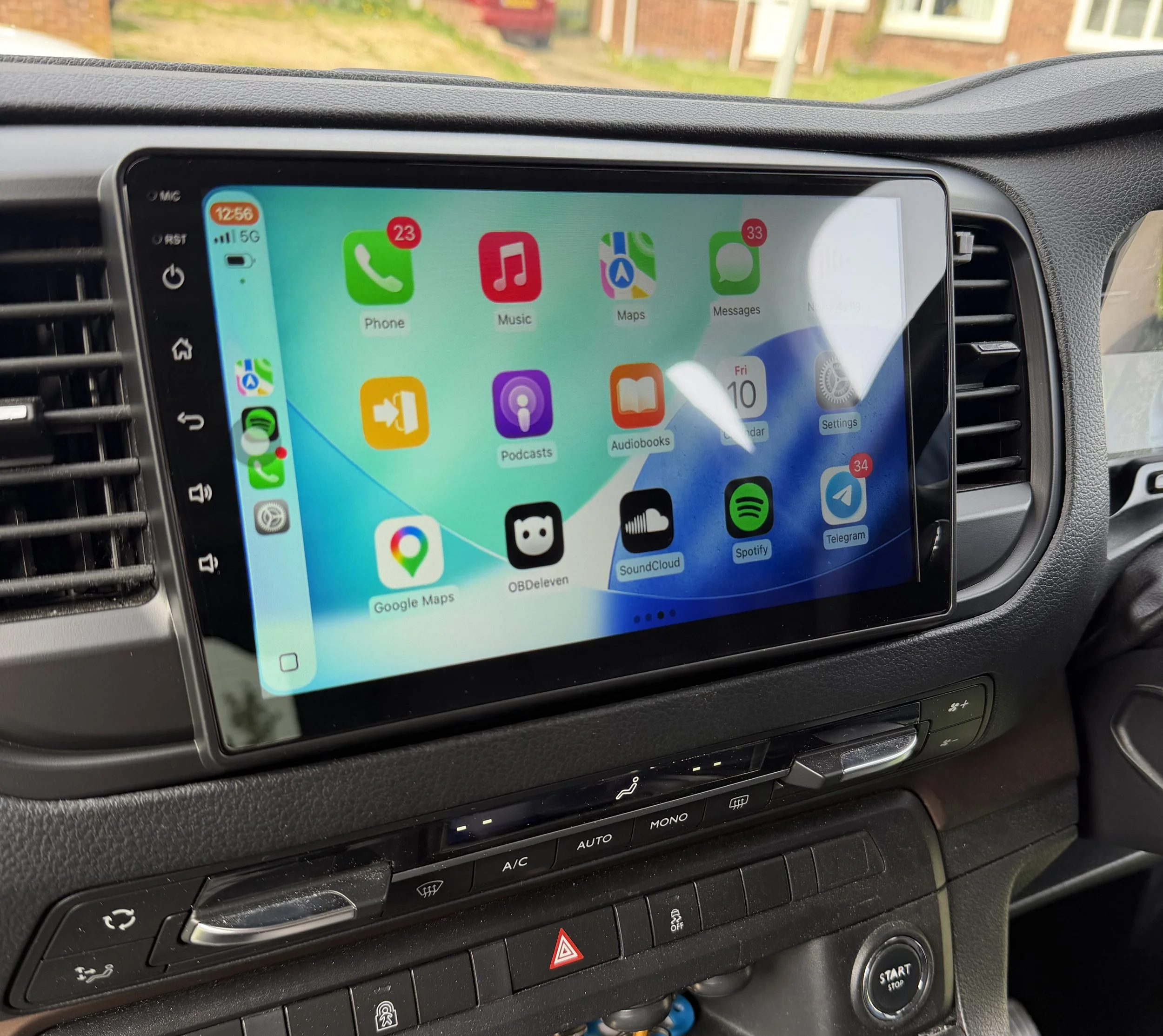Car dashboard showing a touchscreen with app icons including Phone, Music, Maps, Messages, Podcasts, Audiobooks, Calendar, Settings, Google Maps, OBDeleven, SoundCloud, Spotify, and Telegram.