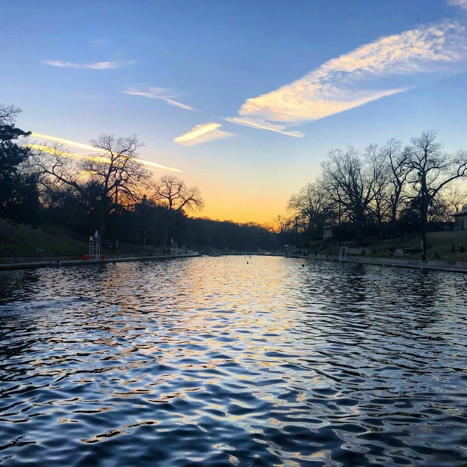 A river at sunset with trees along the banks and clouds in the sky.