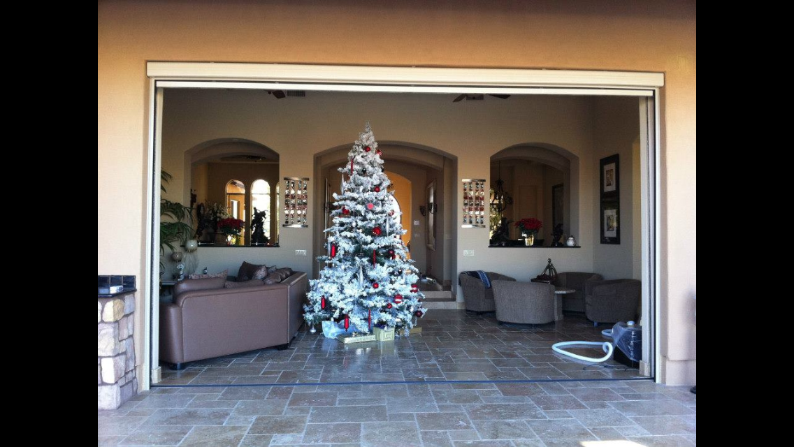 Decorated white Christmas tree in a living room with sofas and potted plants