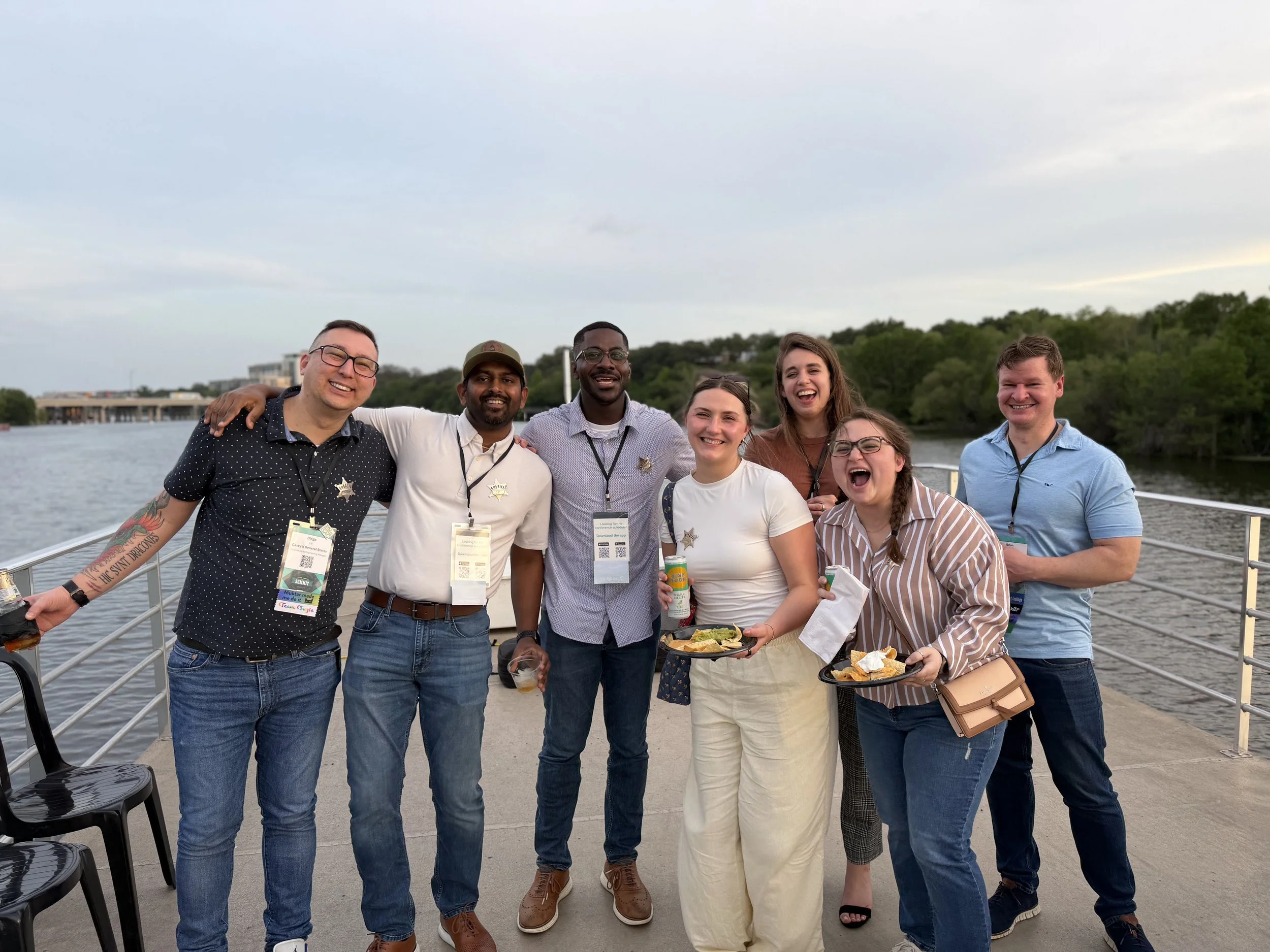 Desert garden scene with cacti, shrubs, and trees, a group of white chairs and tables, and a sign on an easel in the background, under a clear blue sky.