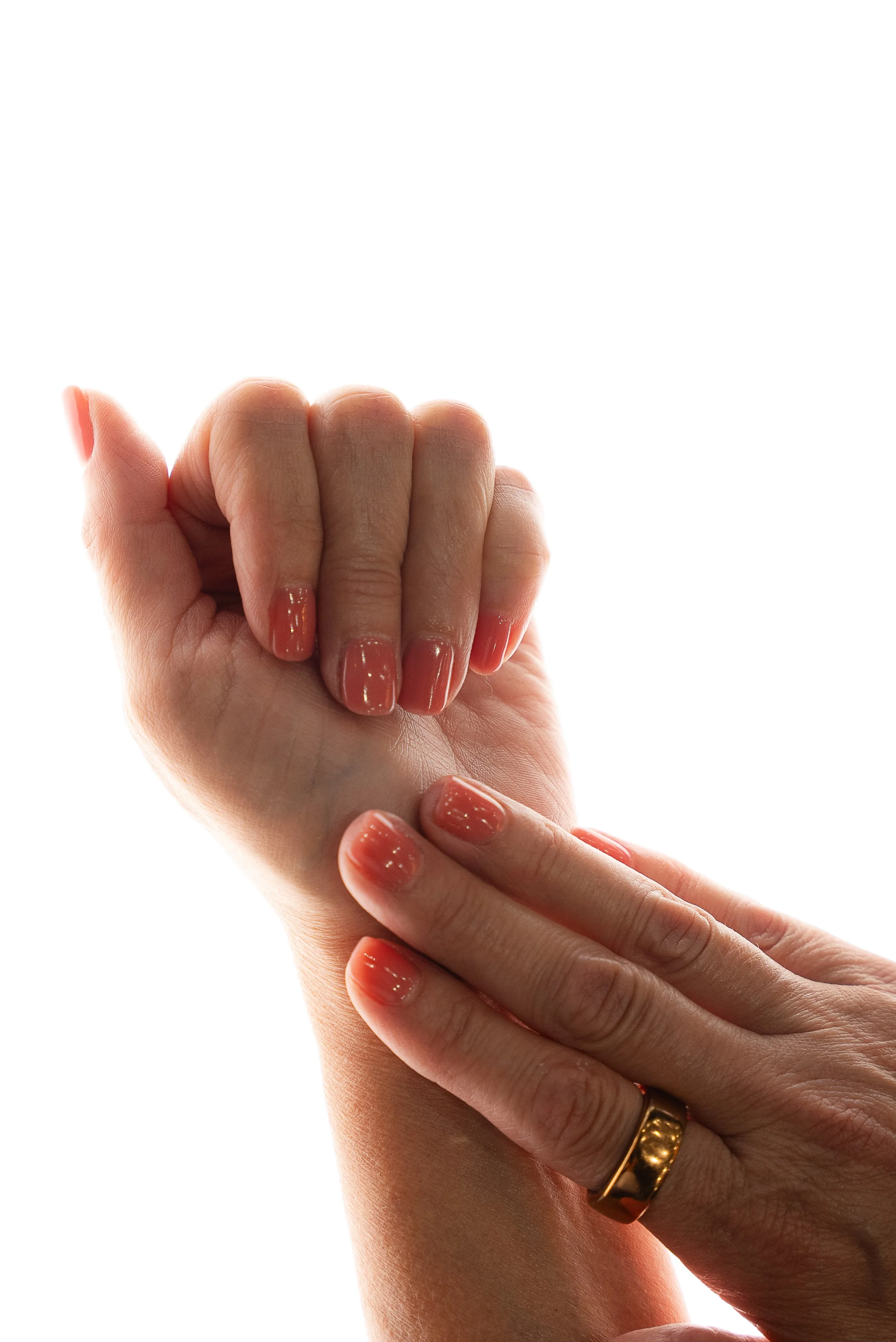 Close-up of a person's hand with freshly painted nails touching another person's wrist against a white background.