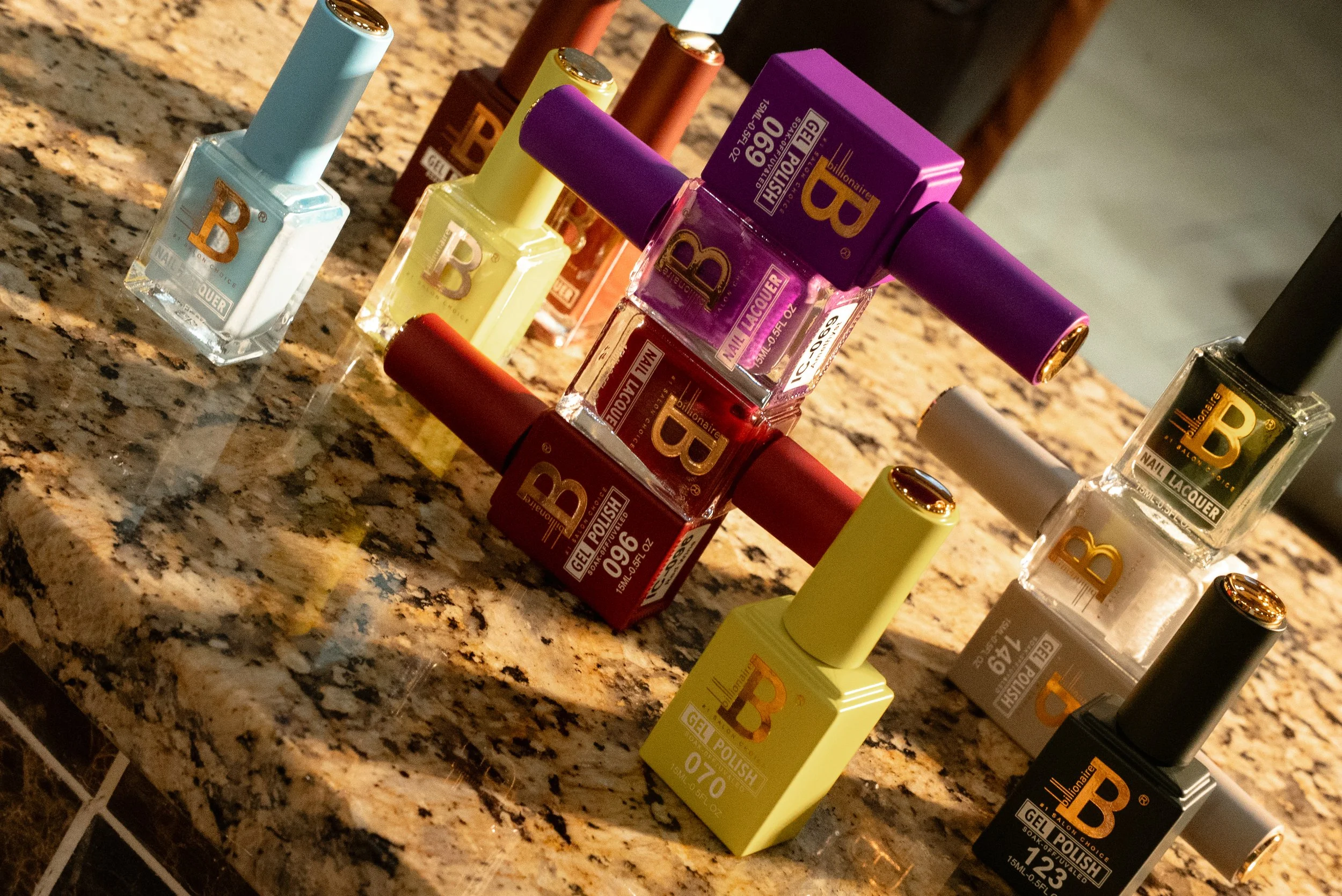 A collection of nail polish bottles in various colors arranged on a speckled granite countertop.