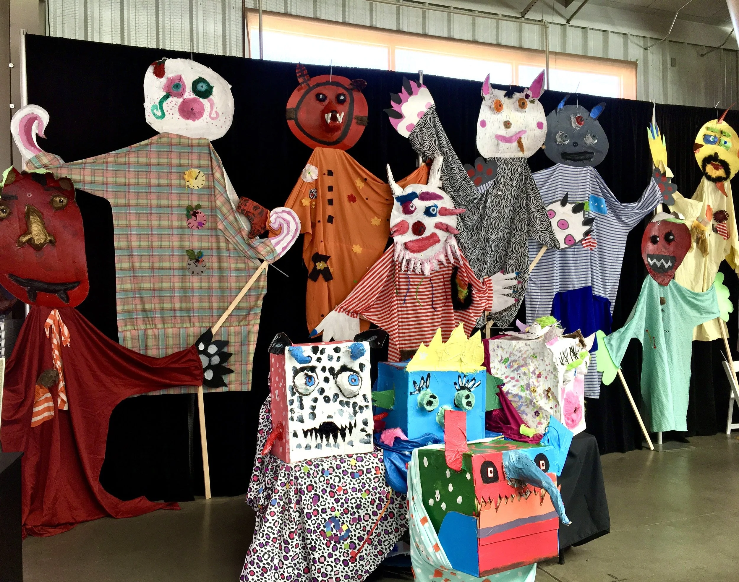 Giant Flat Head and Box Head dragon puppets created in multiple elementary classrooms installed at city-wide youth art exhibition.