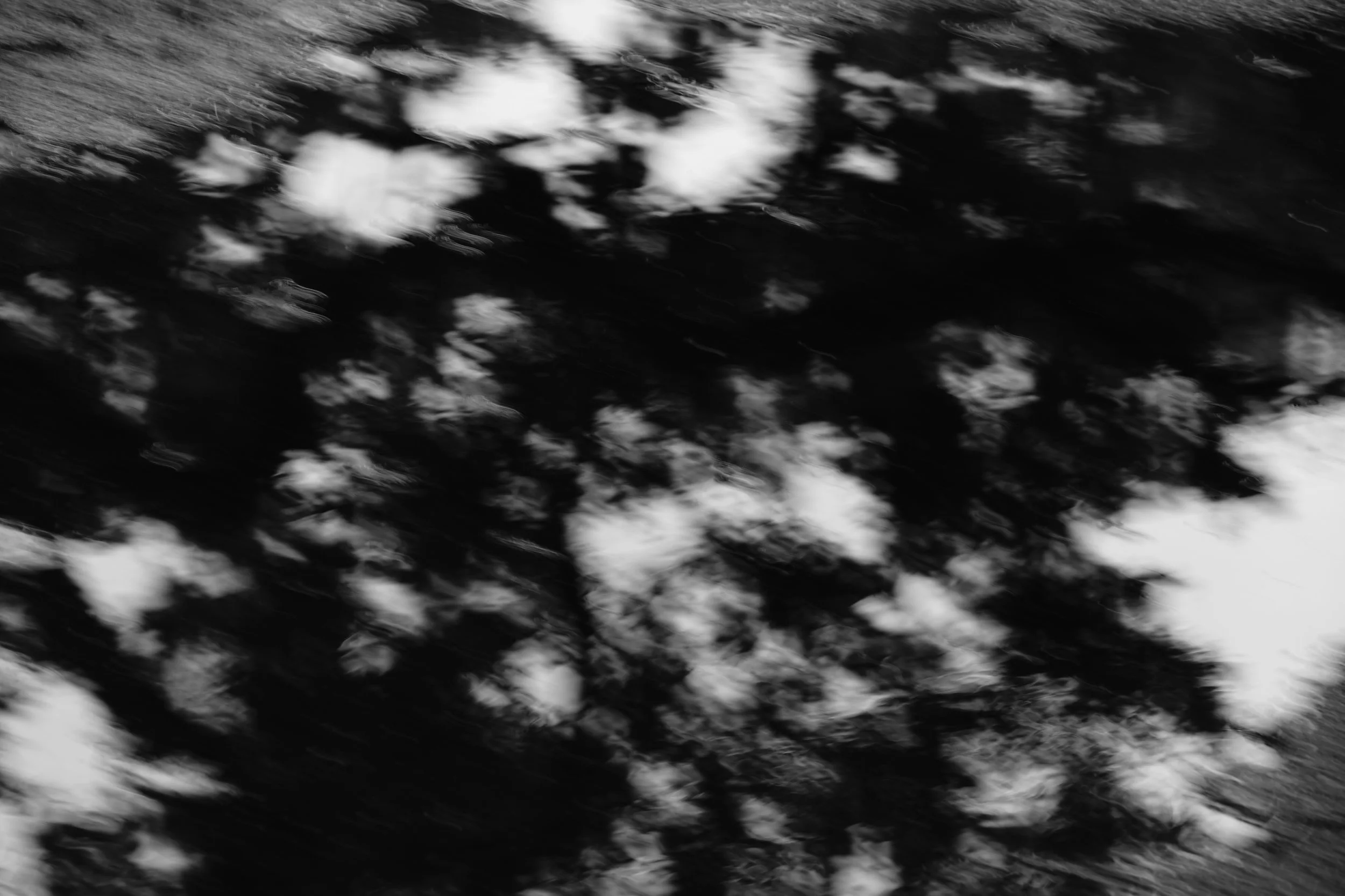 Black and white abstract photo of a cloudy sky reflected on water.