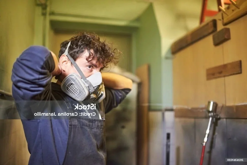 Worker putting on OSHA approved respirator mask