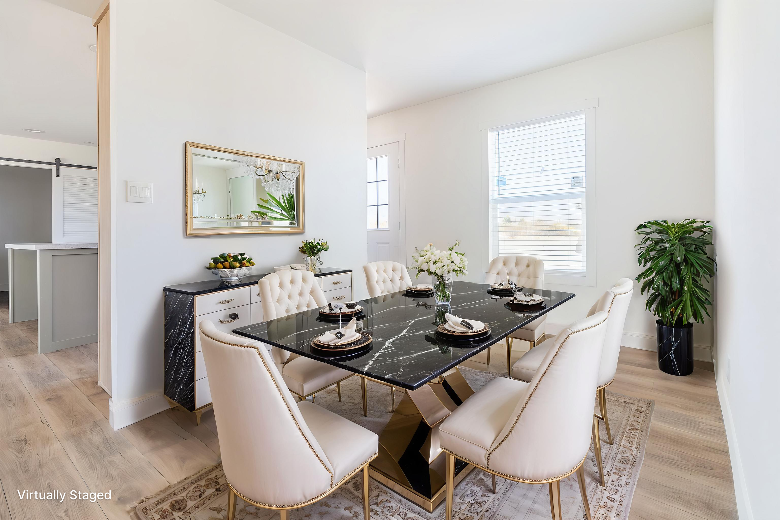 Modern dining room with a black marble table and cream upholstered chairs, large windows, a white sideboard with a mirror above, and a potted plant in the corner.