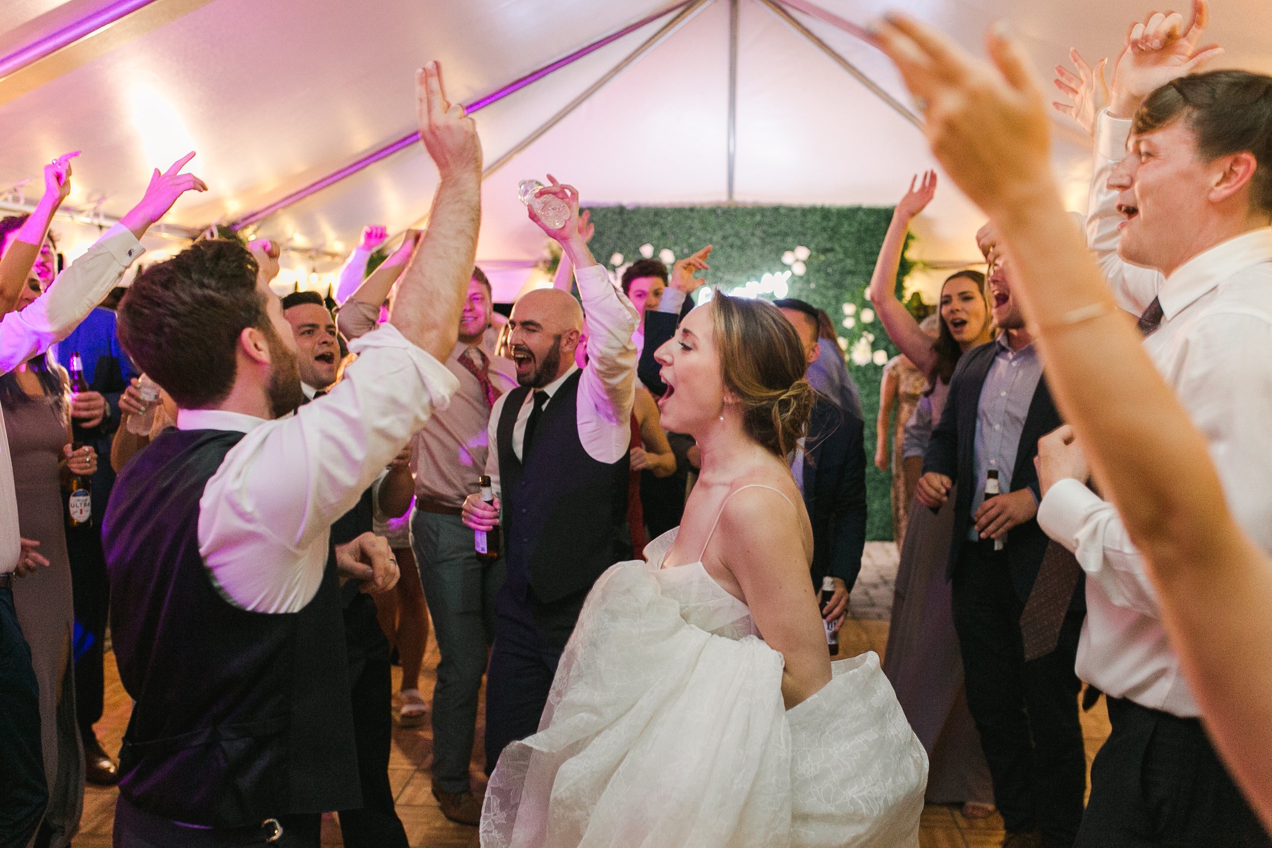 Wedding reception with people dancing and celebrating under a tent.