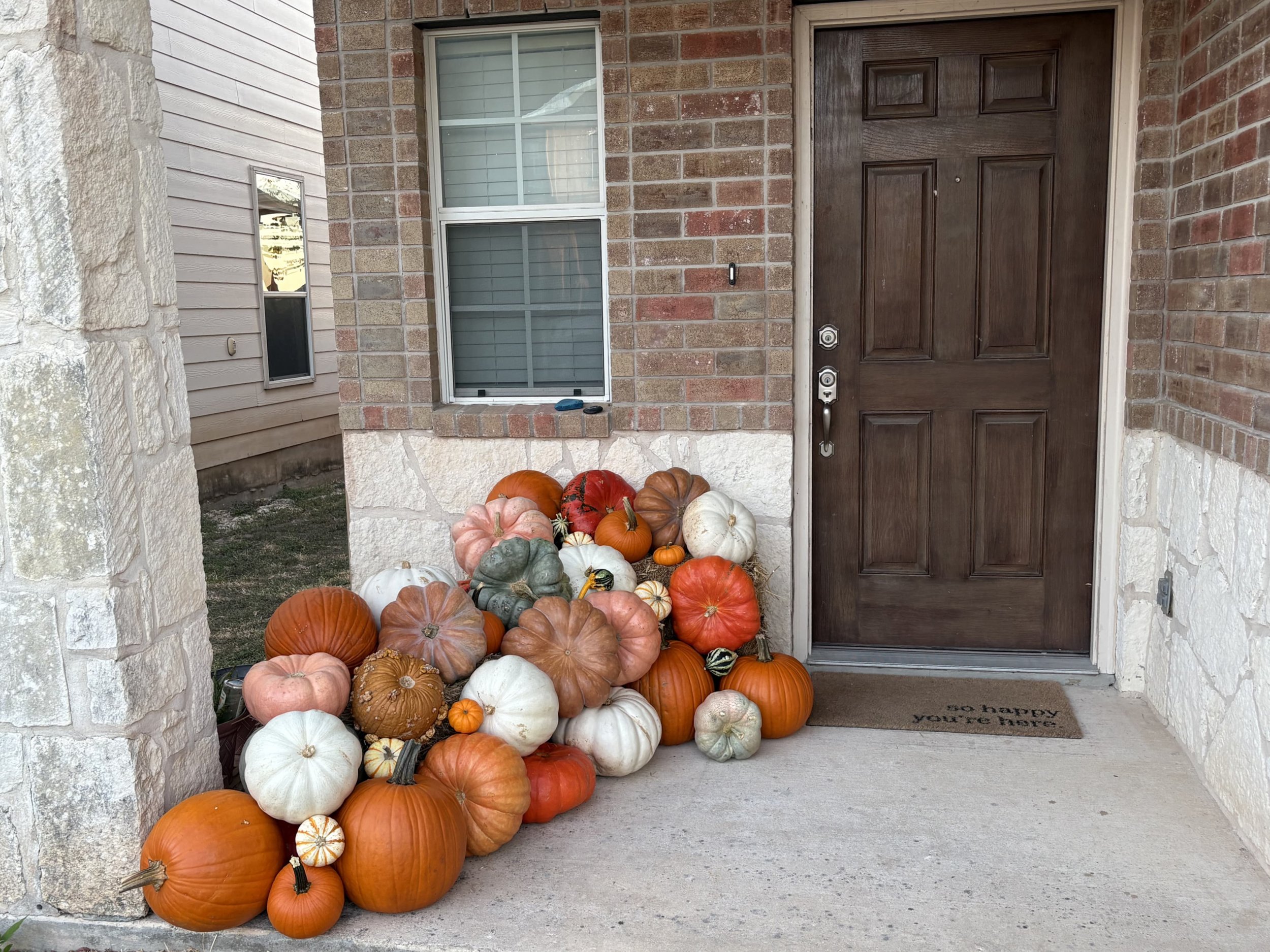 Fall porch decorated with jack o' lanterns, Cinderella pumpkins, Crystal Stars, and hay bales by The Pumpkin Parlor in San Antonio