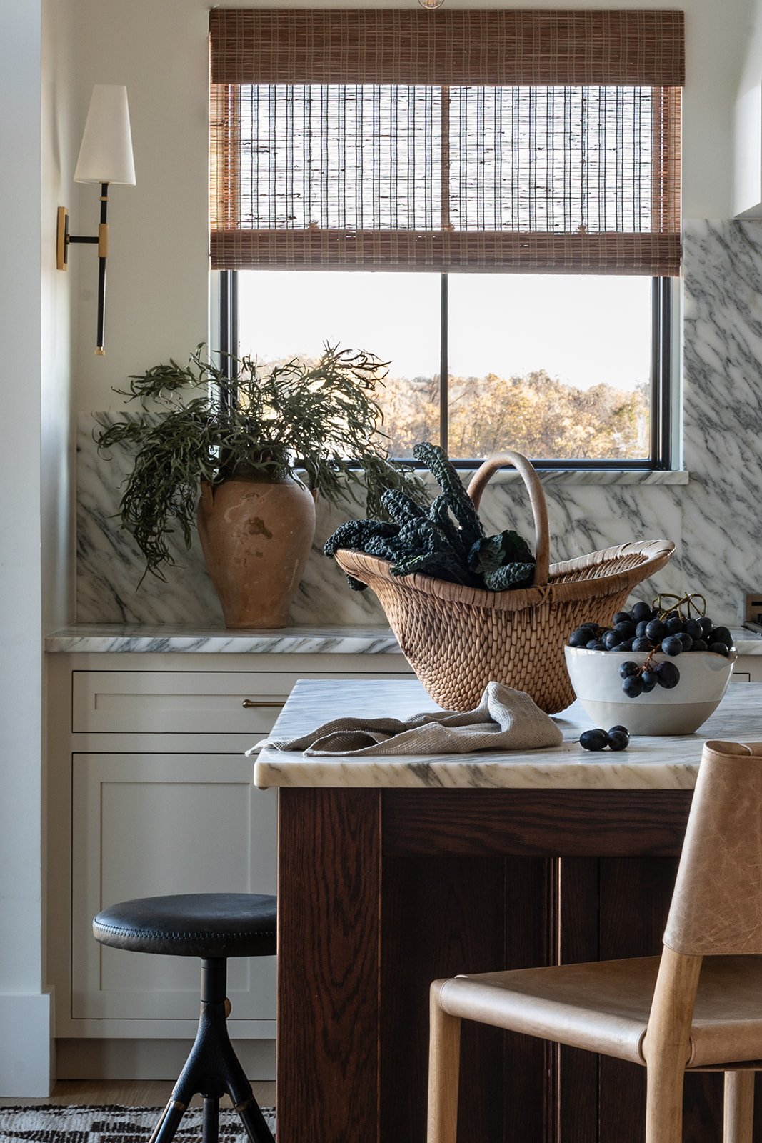 Interior design photography of a warm kitchen nook with marble backsplash, woven basket, and natural light. Captured by Natalie Folchi for an editorial home tour or interior branding feature.