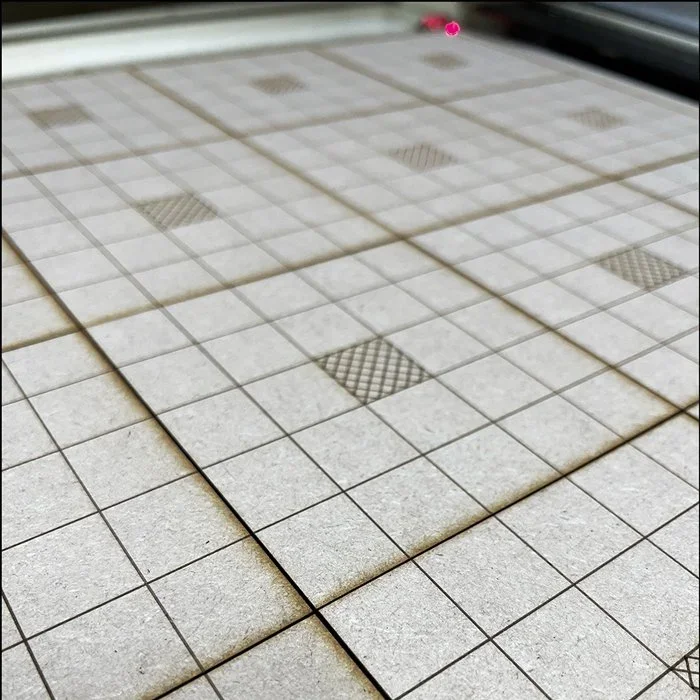 Close-up of a tiled surface with plain and textured tiles arranged in a grid pattern.