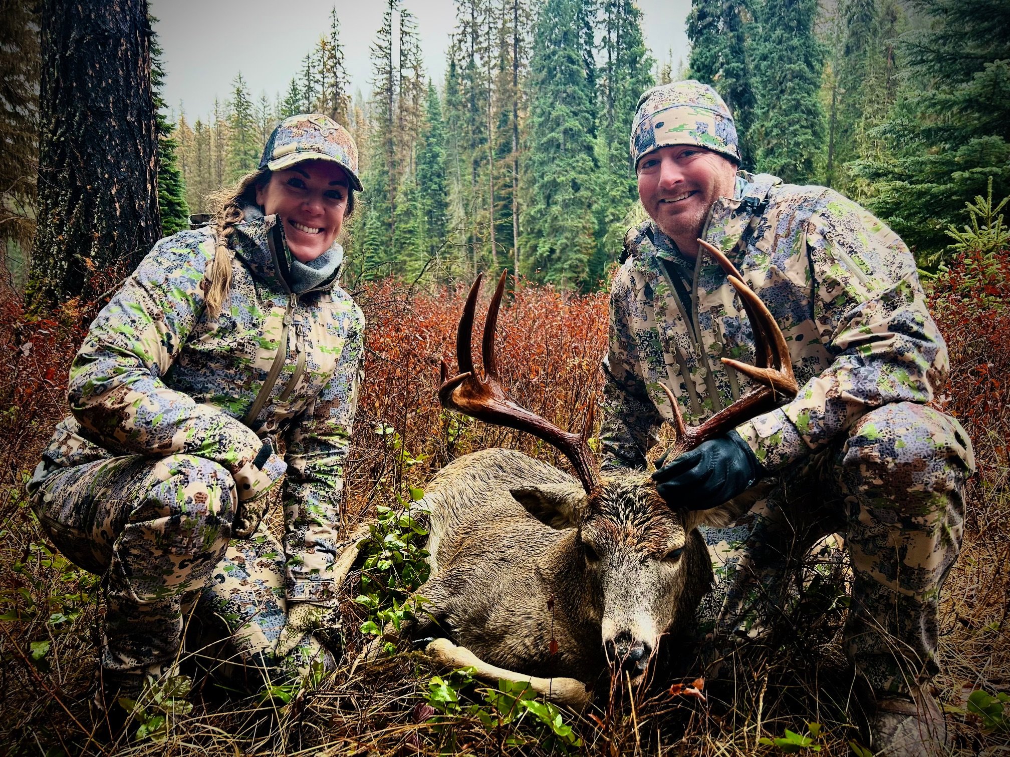 man and woman in camo with whitetail buck