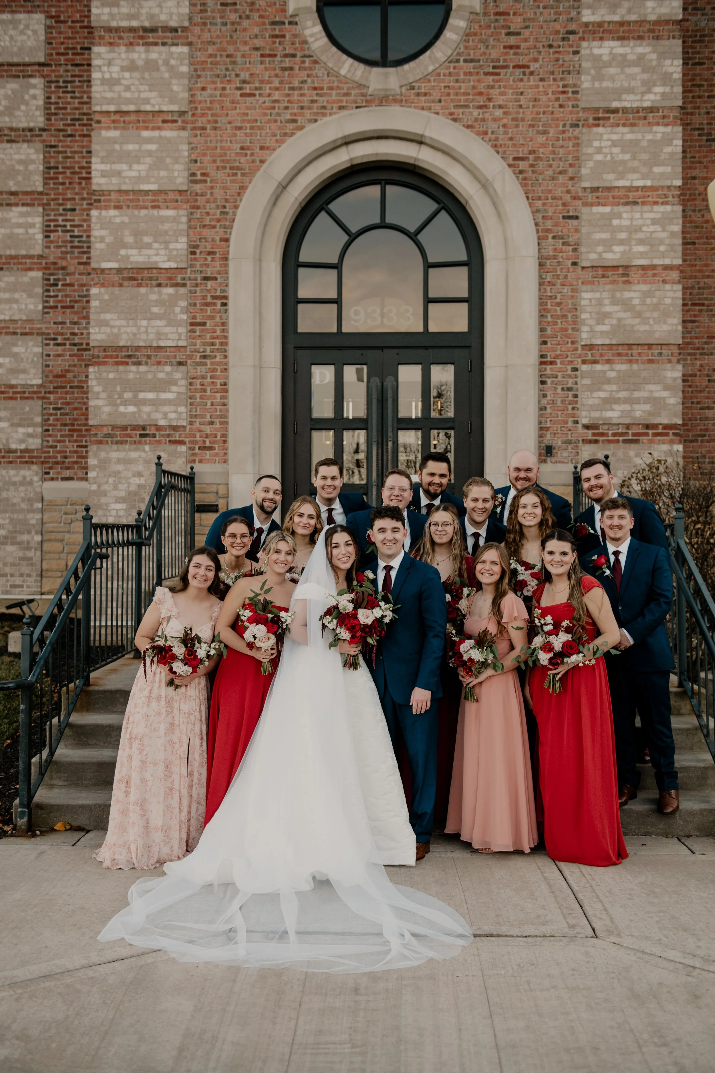 A wedding party standing outside of a church posing for a group photo