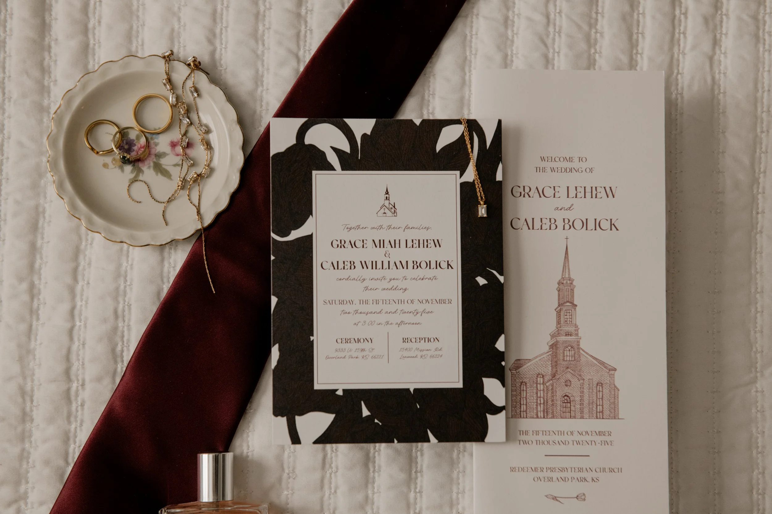 A flatlay of invitation, program, tie, perfume & jewelry
