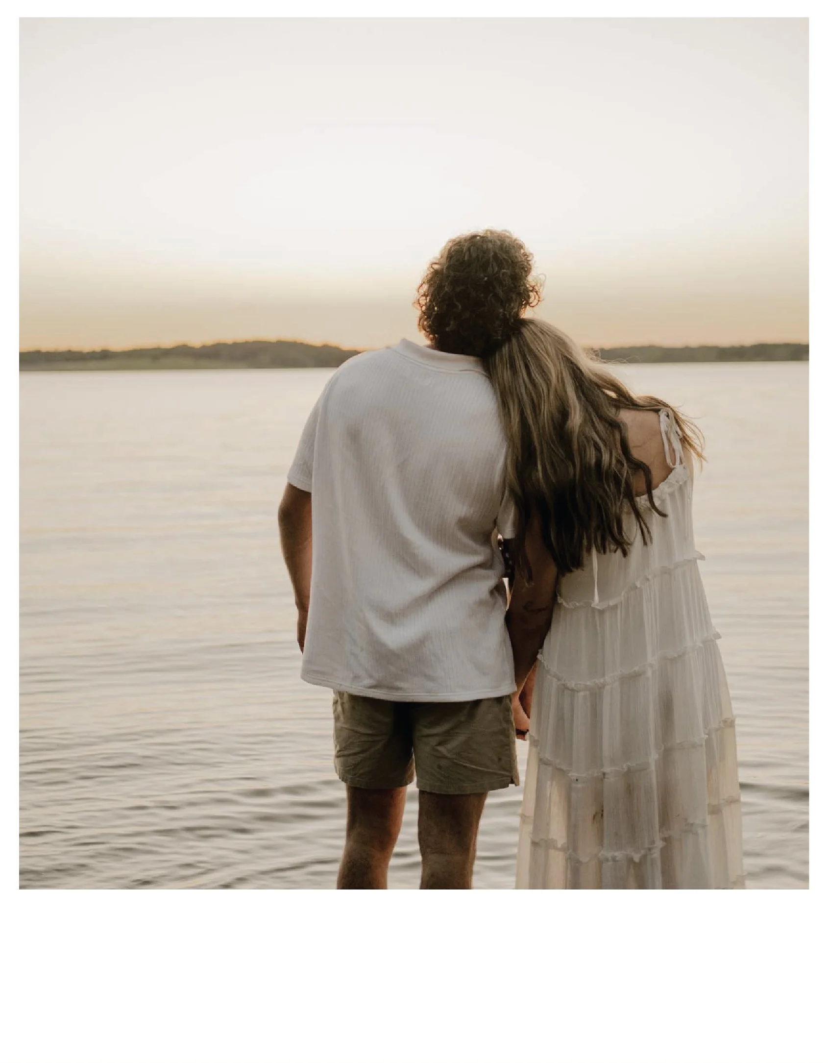 A couple standing by a lake at sunset, embracing and looking at the water at Smithville Lake in Smithville, Missouri