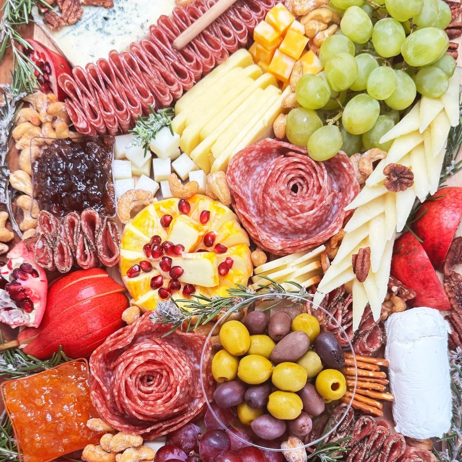 A close-up view of a charcuterie board with assorted cheeses, cured meats, grapes, crackers, nuts, and fruits arranged decoratively.