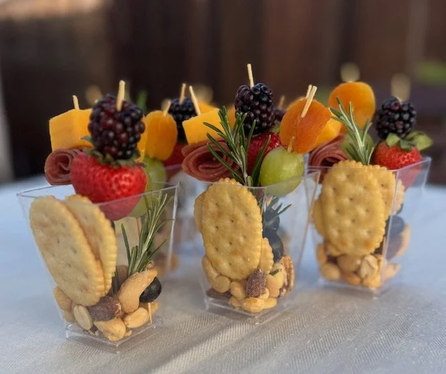 Cheese and meat charcuterie cup with grapes, olives, rosemary sprigs, crackers, and skewered cheese cubes