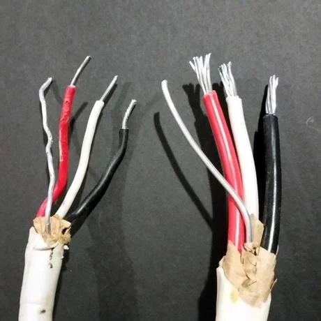 Close-up of two bundles of stripped electrical wires with exposed copper ends, wrapped in brown paper, against a dark background.