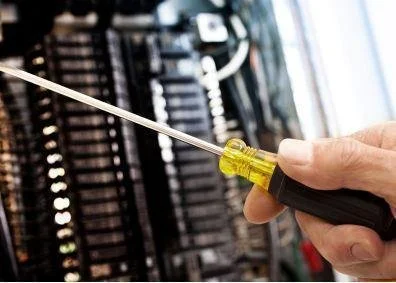 A person using a screwdriver to work on a server or computer hardware.