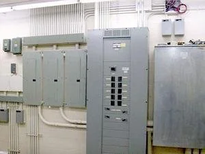 Electrical control panels and circuit breakers mounted on a wall in an industrial setting.
