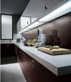 Modern kitchen with dark cabinets, white countertops, and appliances, with fresh vegetables on cutting boards.