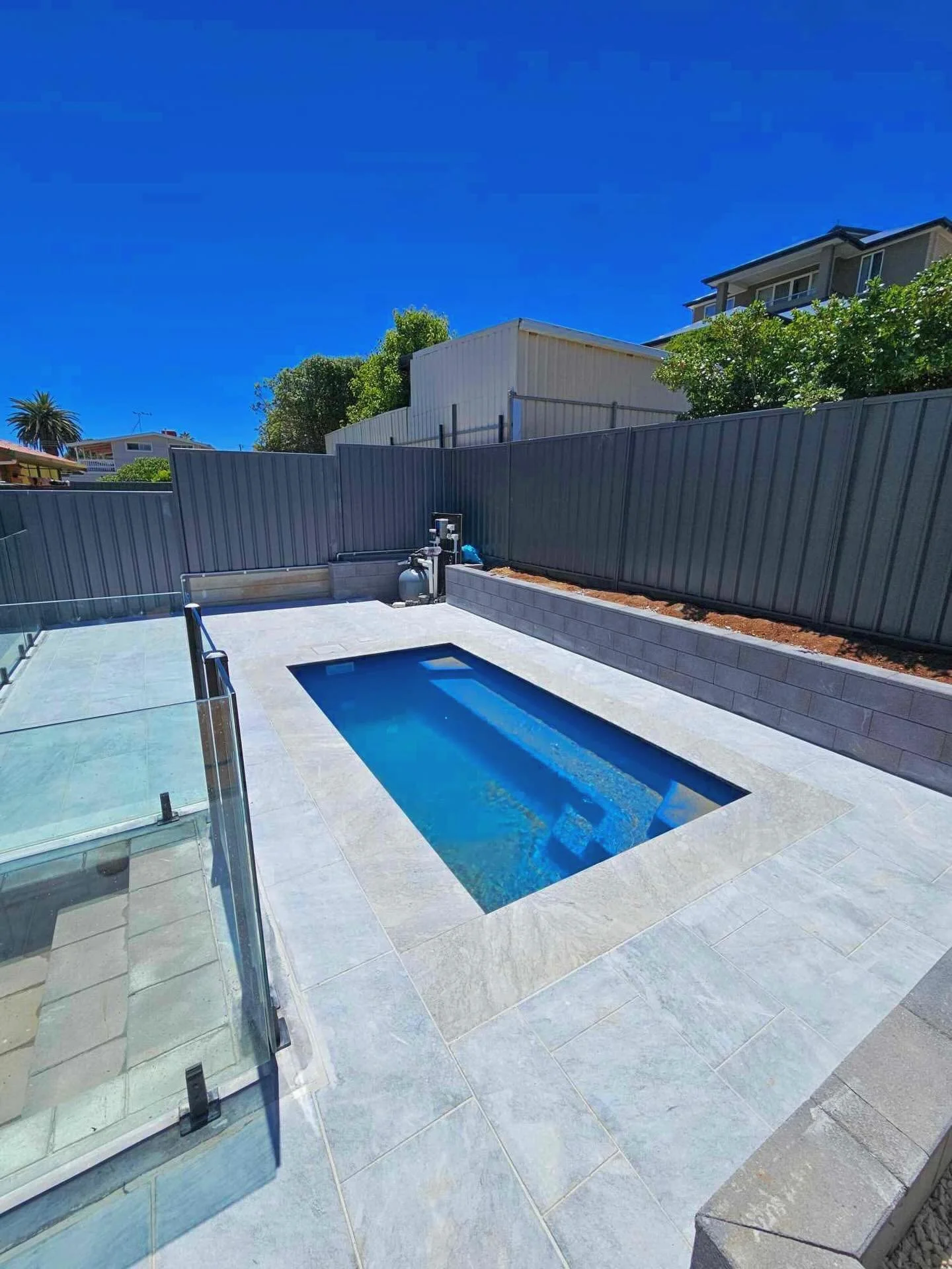 Such a great finish on this pool with these natural grey marble pavers. 
Wet lay on concrete slab with a complementing versa-stone wall.