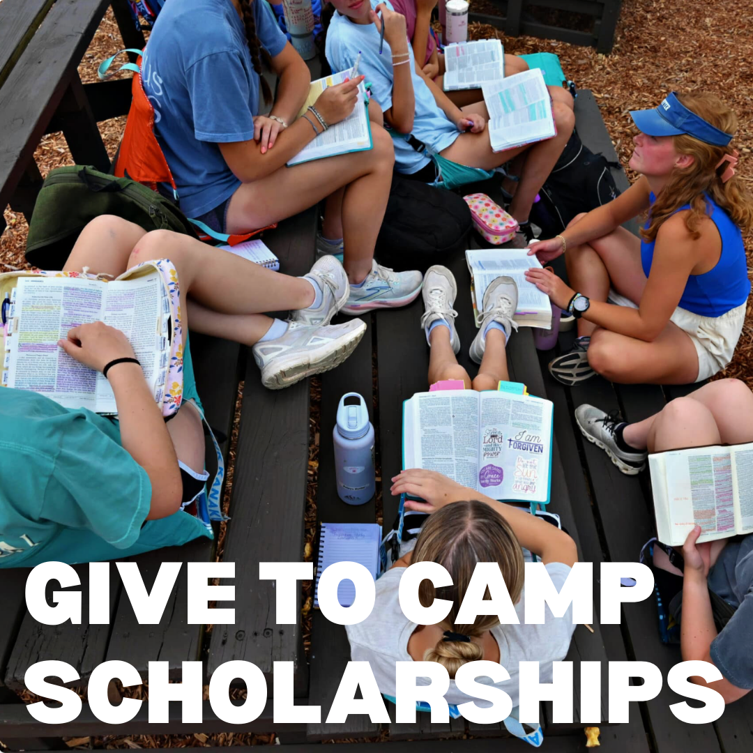 A group of children sitting on a picnic table with open Bibles and notebooks, outdoors on wood chips, with backpacks and water bottles, studying or reading together. The text overlay reads 'GIVE TO CAMP SCHOLARSHIPS'.