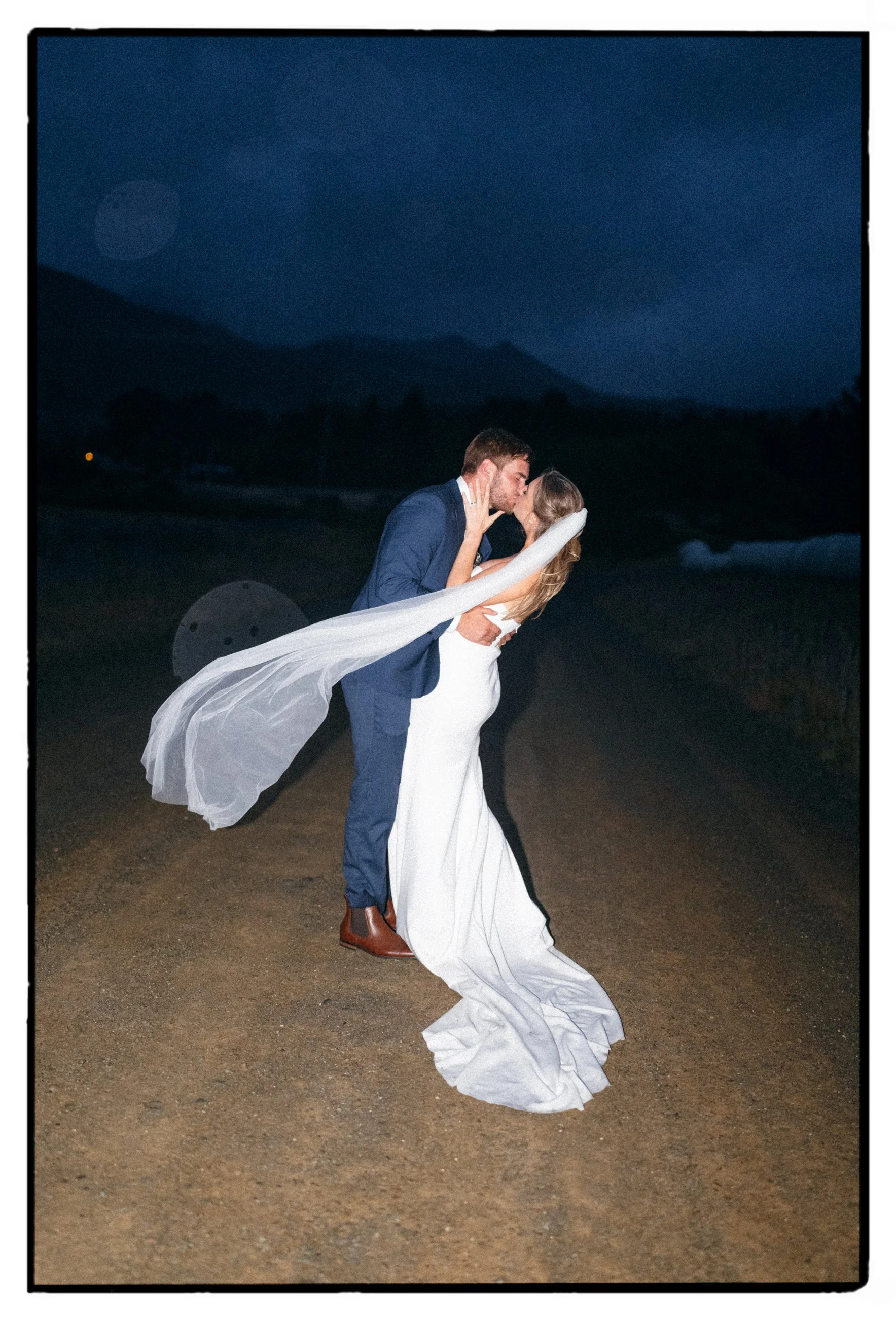 Film + Digital Wedding Photographer Christchurch - Lake Tekapo Wedding, Canterbury, New Zealand. Flash late night photo of bride and groom kissing with mountains in the background.