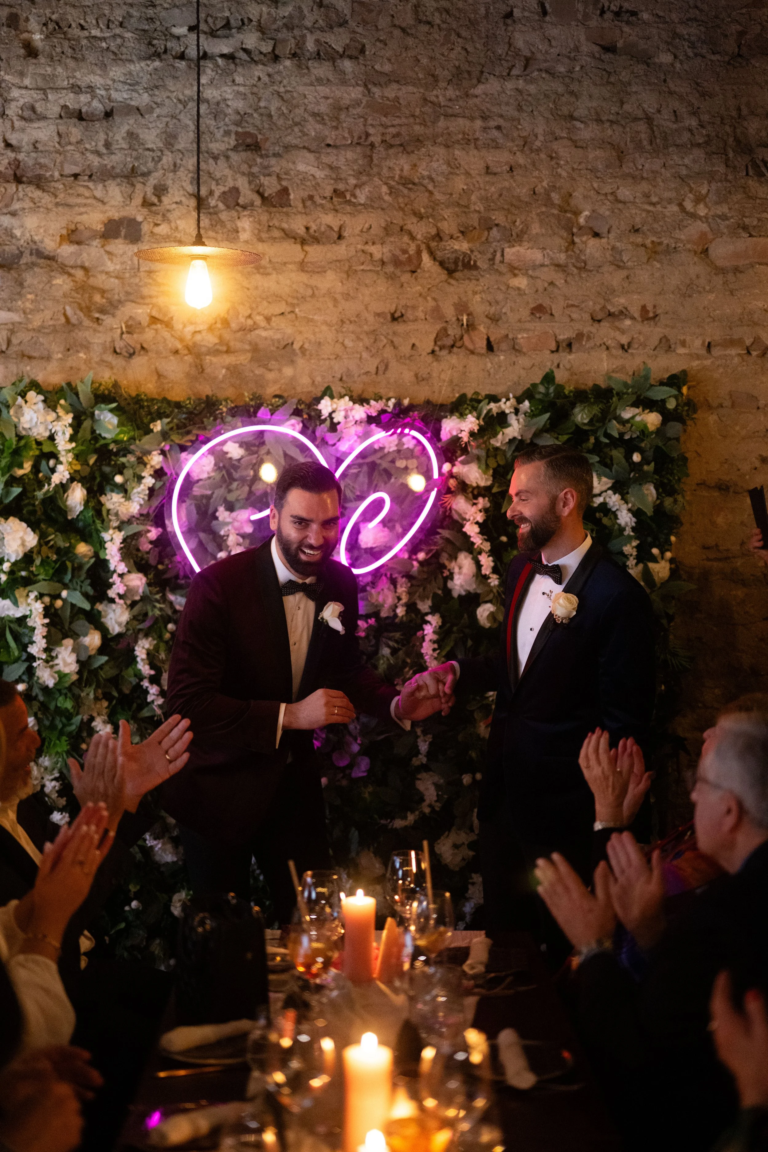 Grooms smiling and guests clapping.